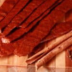 Several strips of pumpkin chicken jerky on a cutting board.