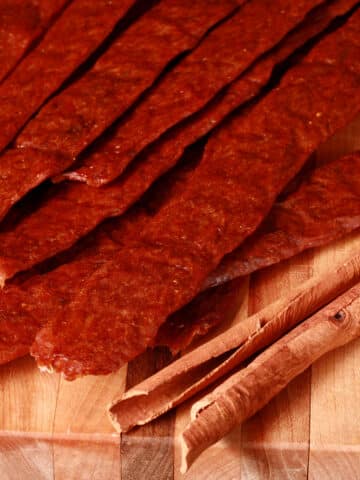 Several strips of pumpkin chicken jerky on a cutting board.