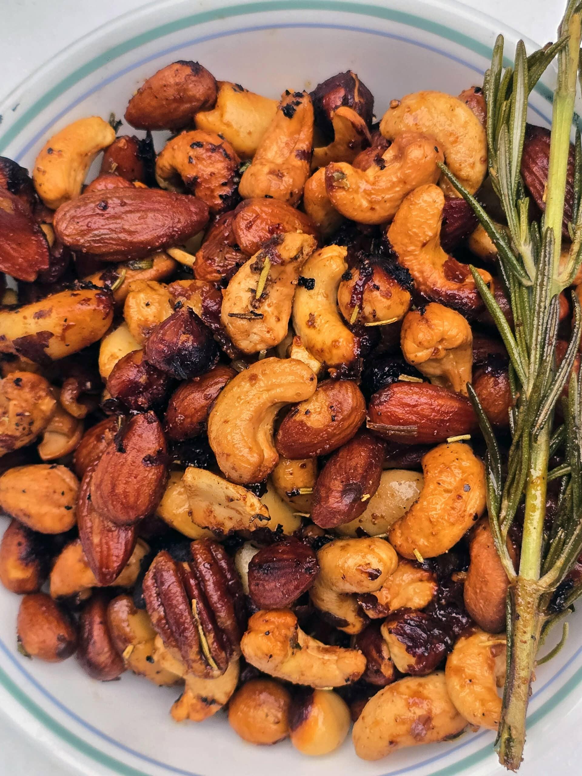 A bowl of campfire roasted spiced nuts on a snowy picnic table.