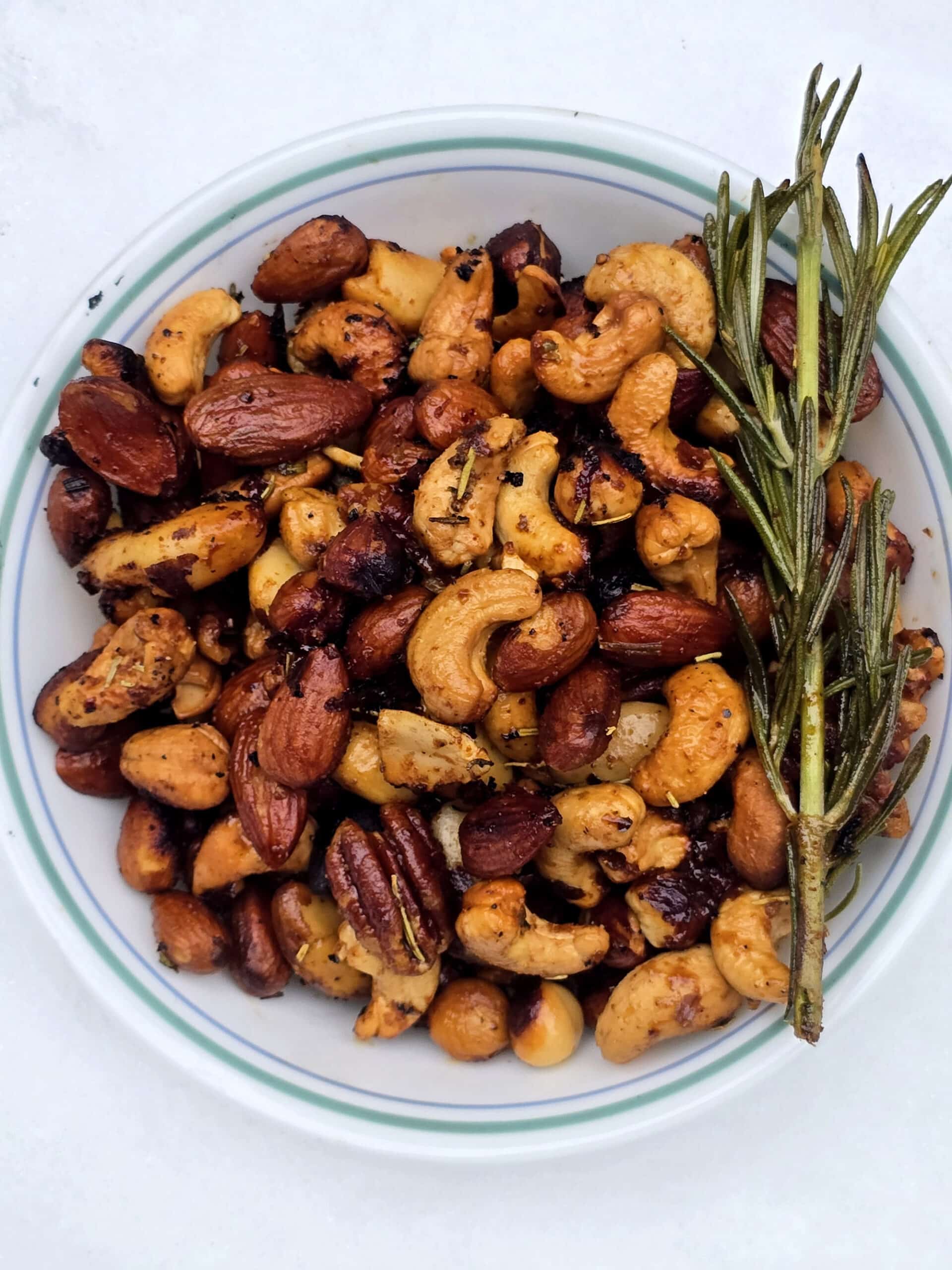 A bowl of campfire roasted spiced nuts on a snowy picnic table.