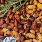 A bowl of campfire roasted spiced nuts on a snowy picnic table.