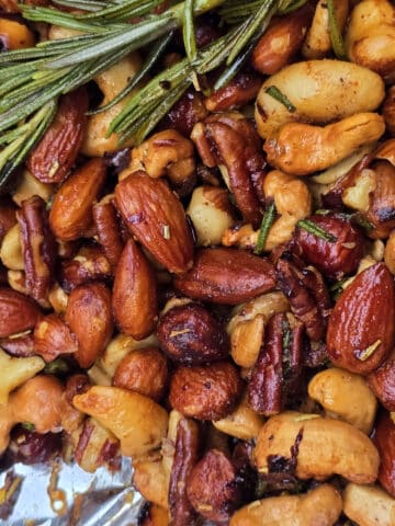 A bowl of campfire roasted spiced nuts on a snowy picnic table.