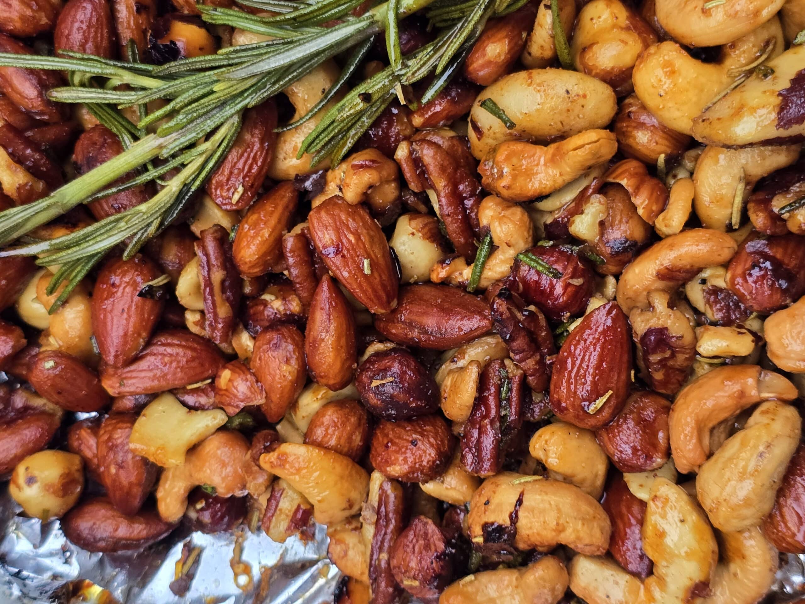 A bowl of campfire roasted spiced nuts on a snowy picnic table.