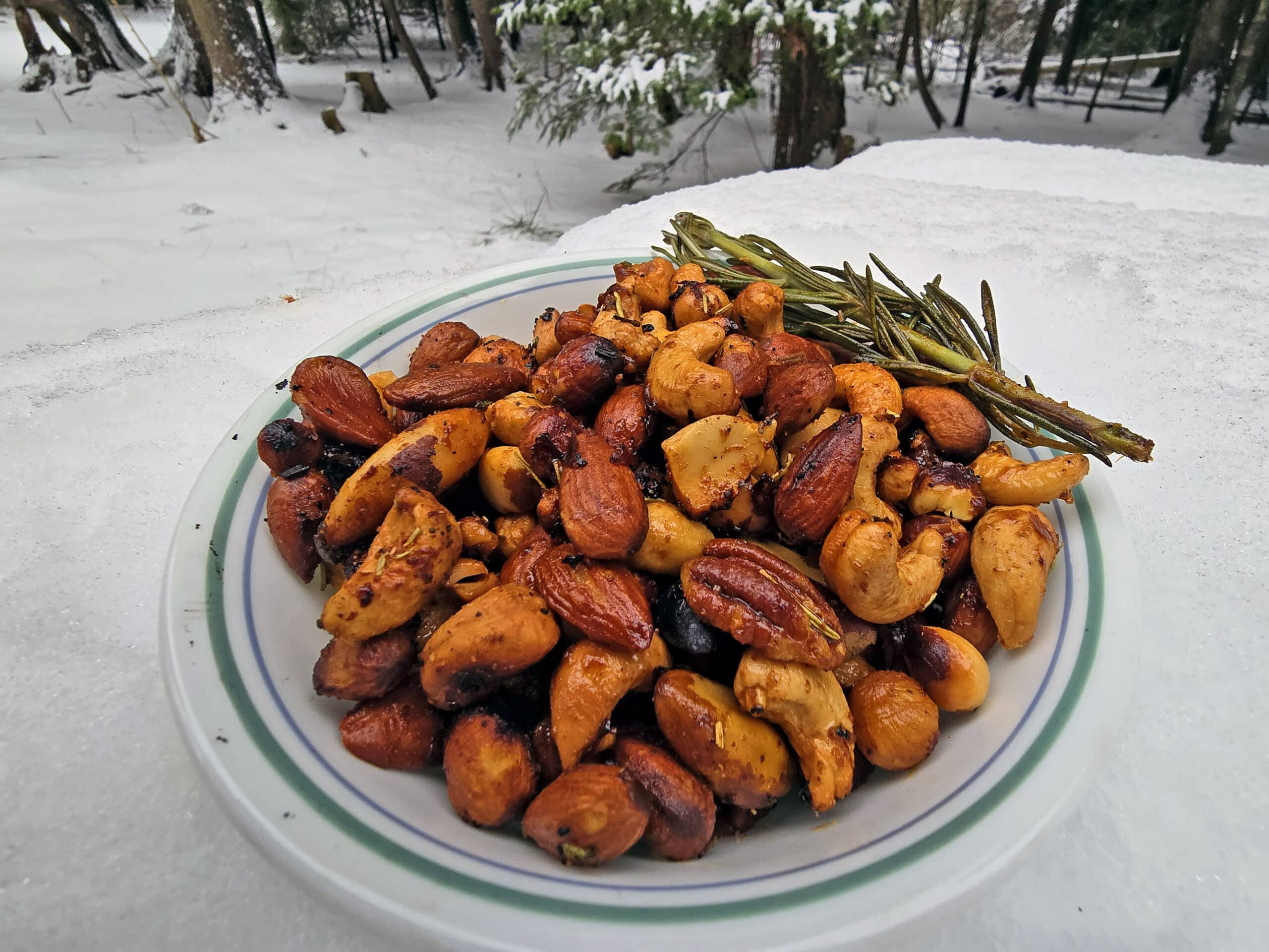 A bowl of fire roasted spiced nuts on a snowy picnic table.