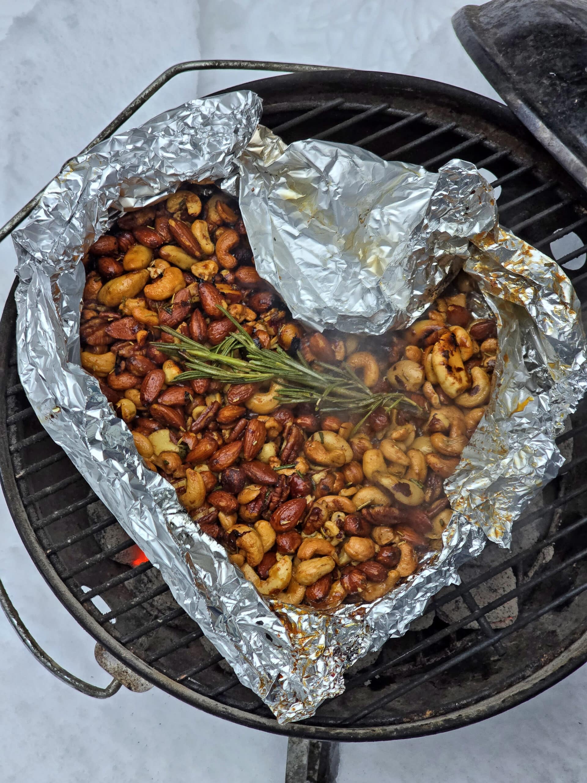 An open foil packet of spiced nuts on a grill.