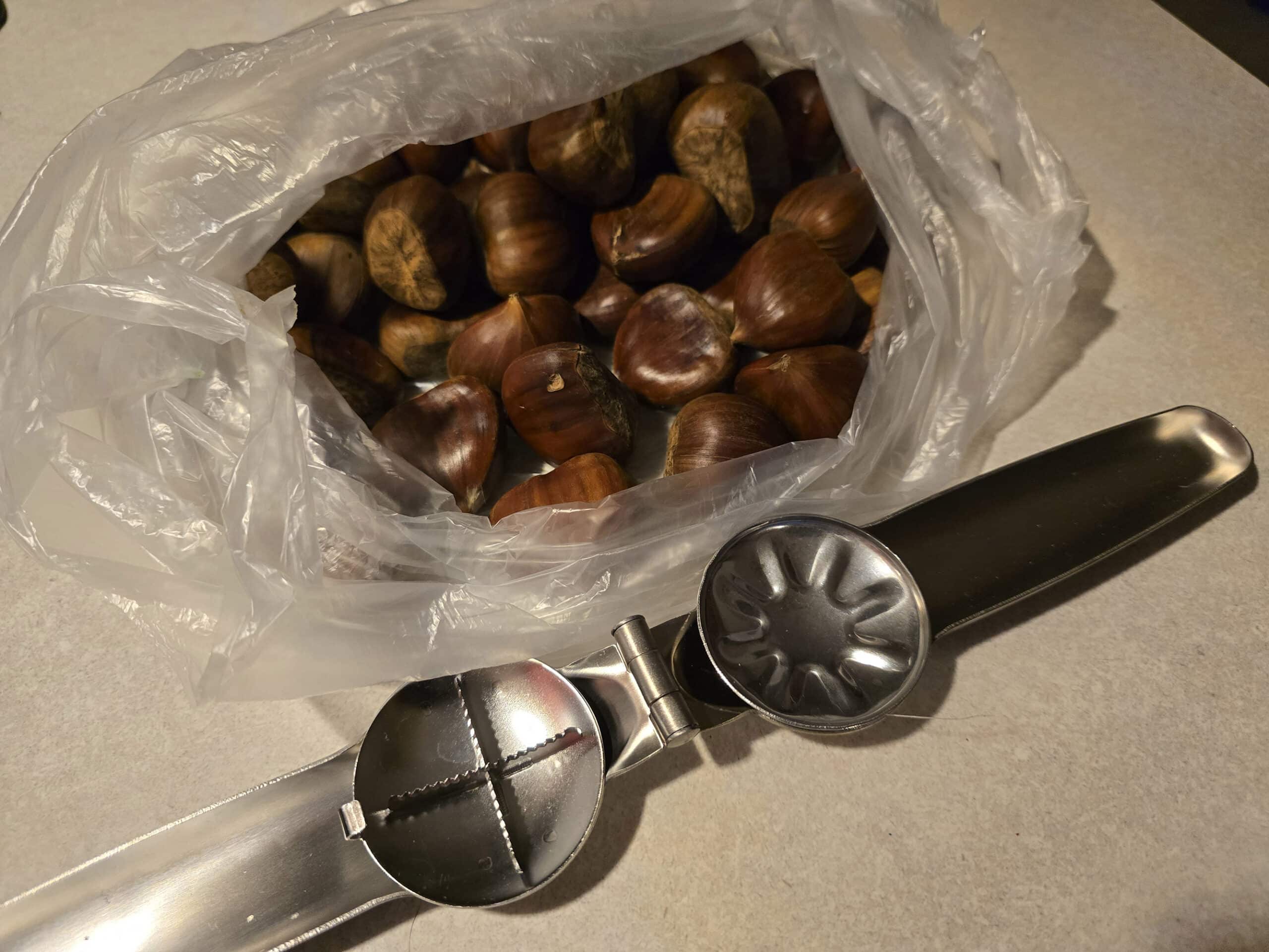 A bag of chestnuts with a chestnut knife in front of it.