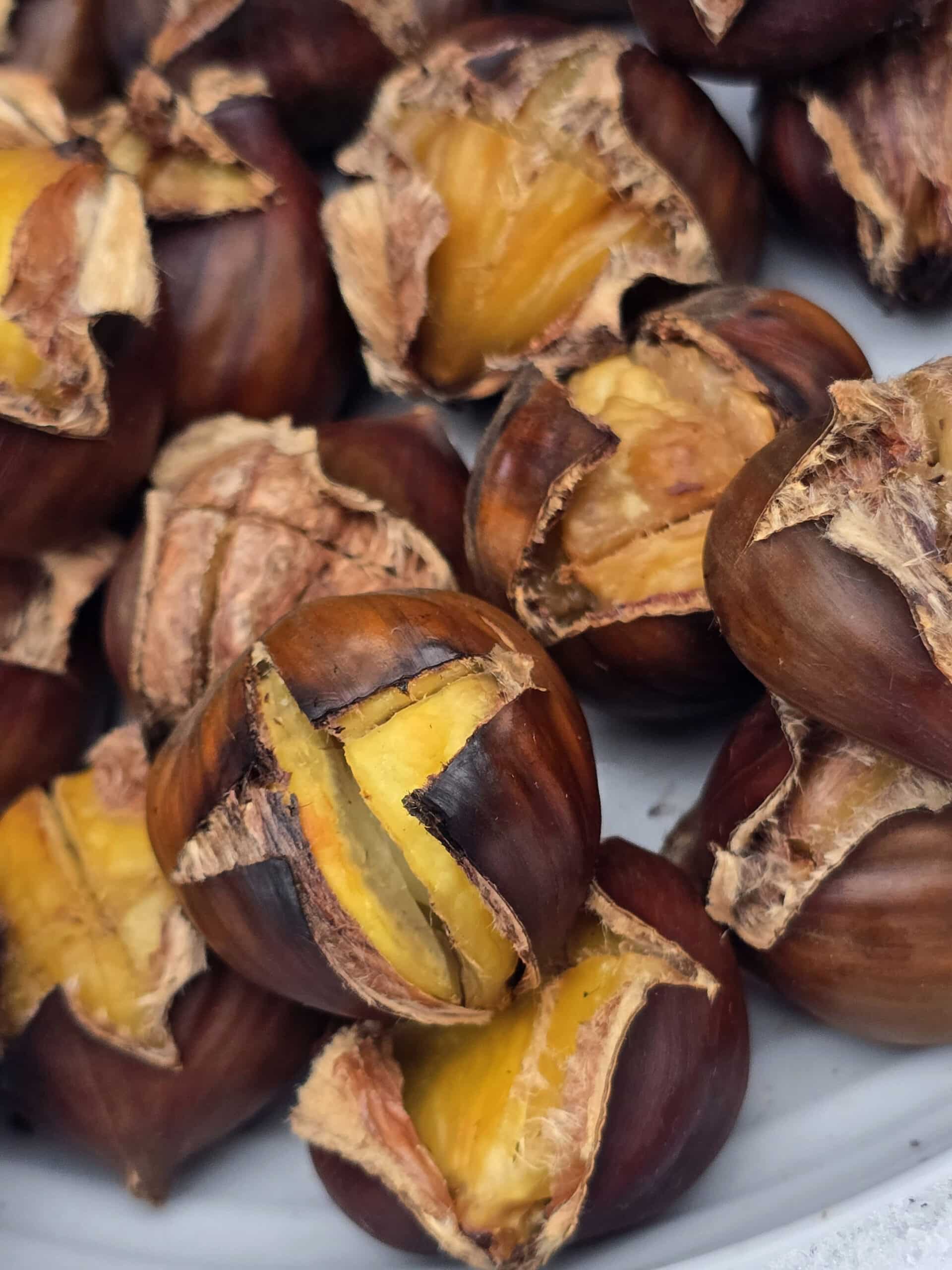 A plate of campfire roasted chestnuts on a snowy picnic table.