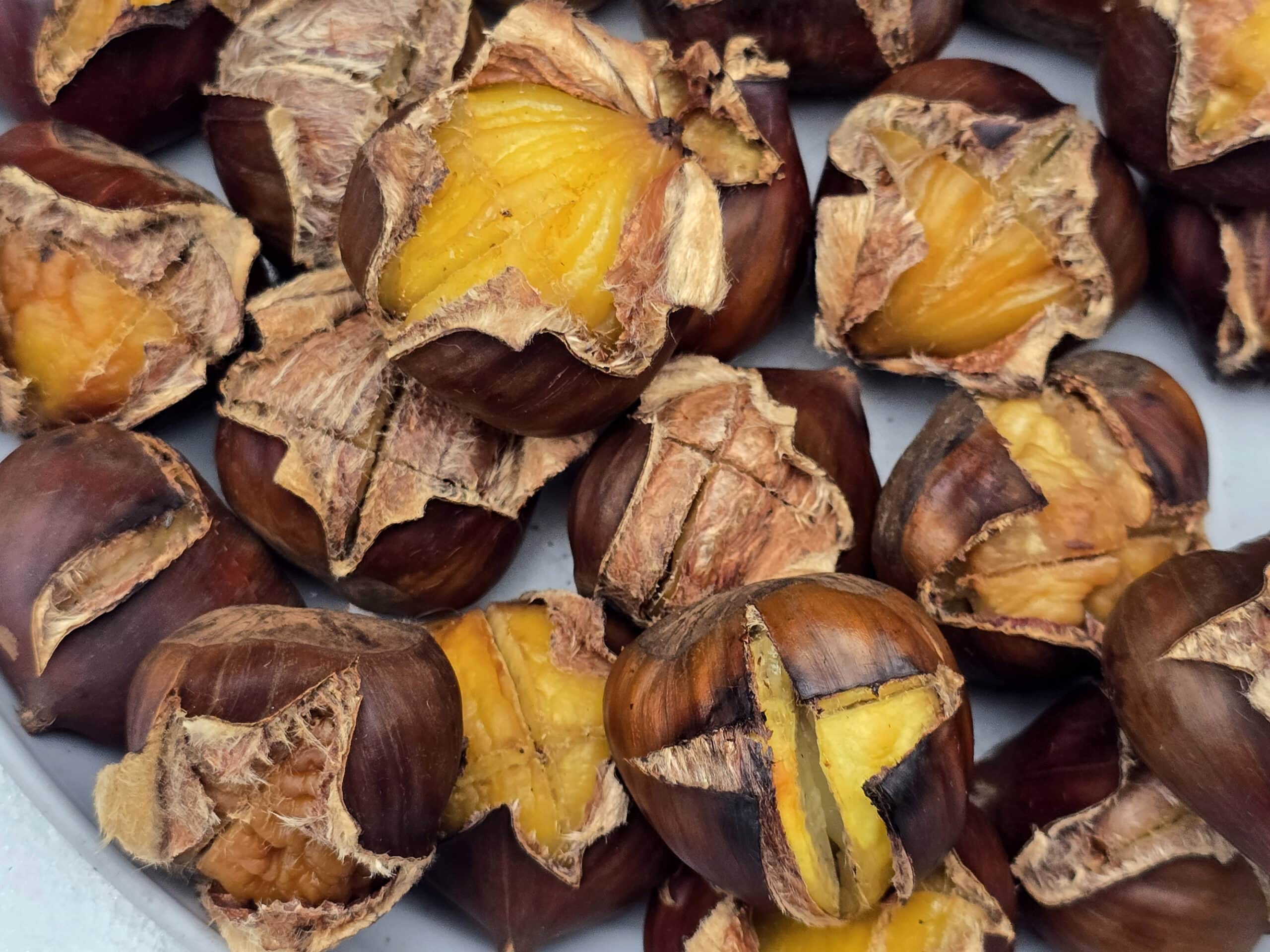 A plate of campfire roasted chestnuts on a snowy picnic table.