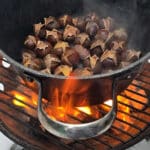 A pot of chestnuts roasting on an open fire.