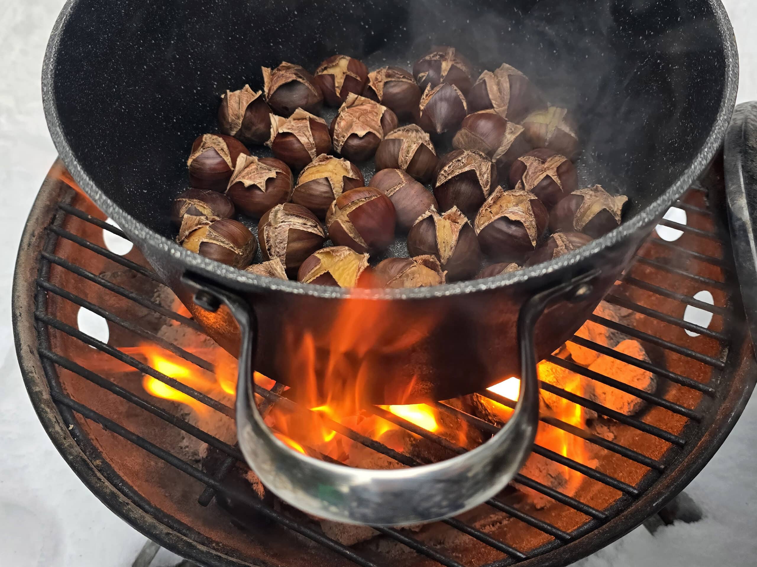 A pot of chestnuts roasting on an open fire.