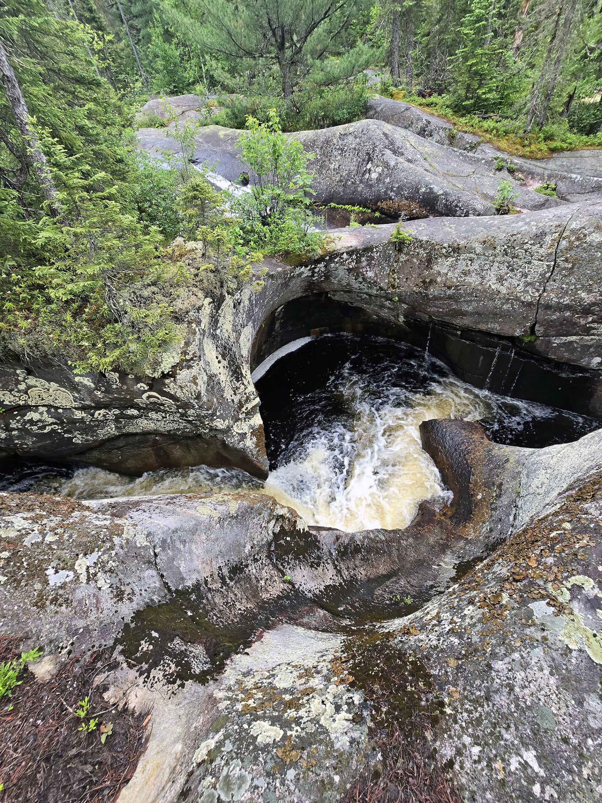 A large glacial pothole with water swirling down into it.