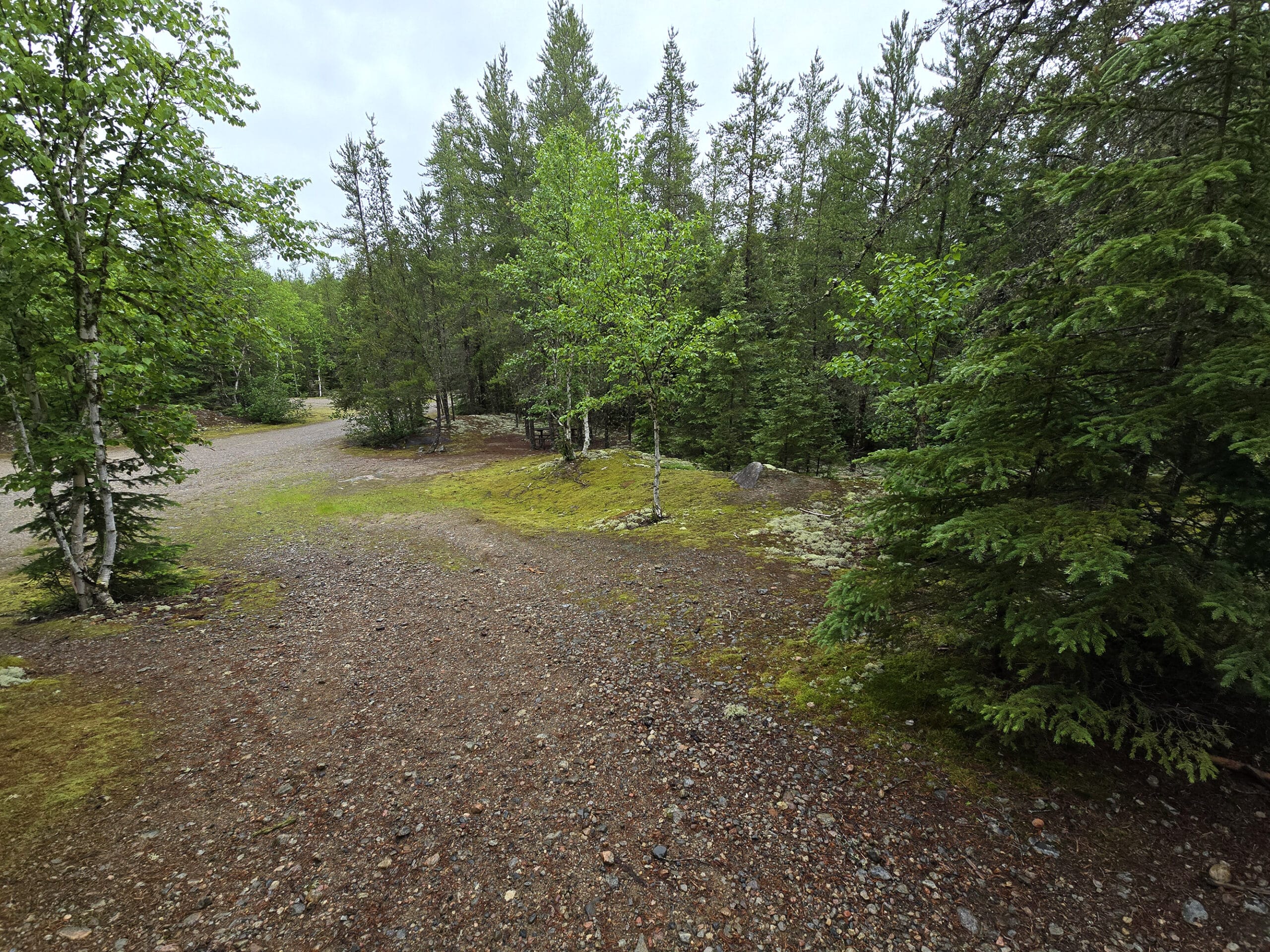 A trail with two picnic nooks and a parking lot in the background.