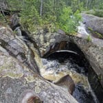 A large glacial pothole with water swirling down into it.
