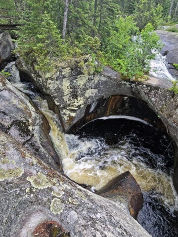 A large glacial pothole with water swirling down into it.