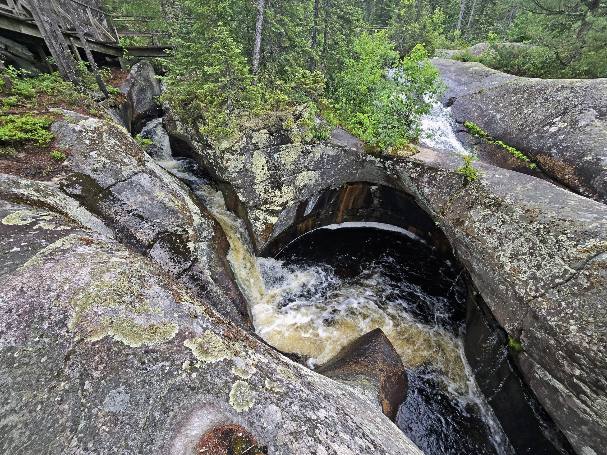 A large glacial pothole with water swirling down into it.