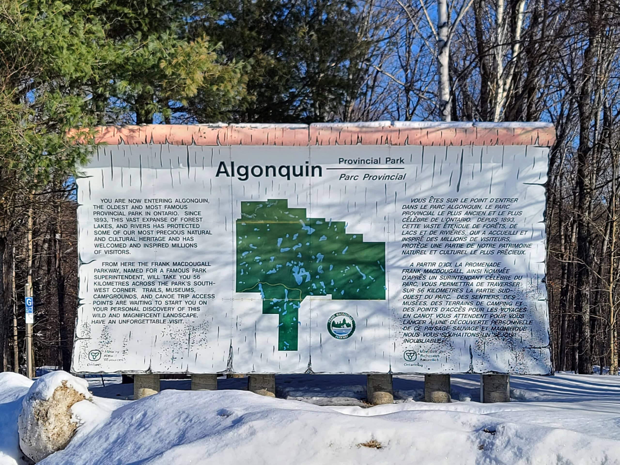 A large algonquin provincial park sign in a snow drift.