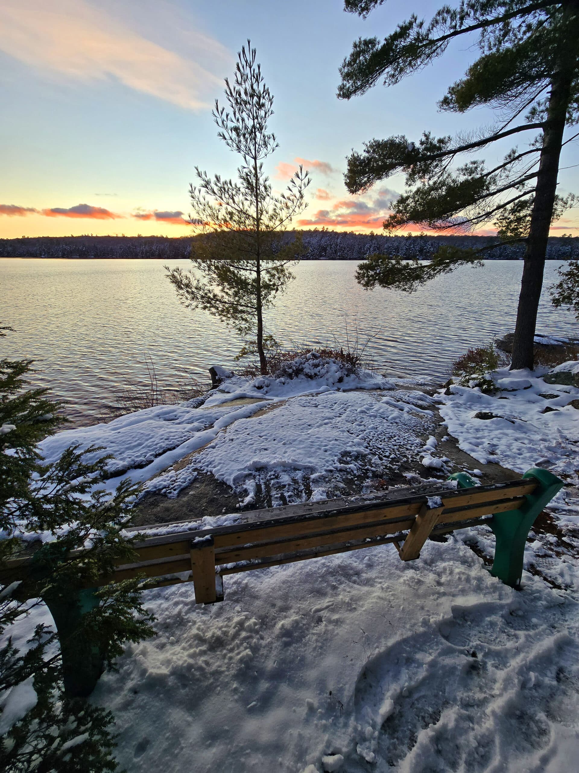 A bench overlooking silent lake on a winter sunset.