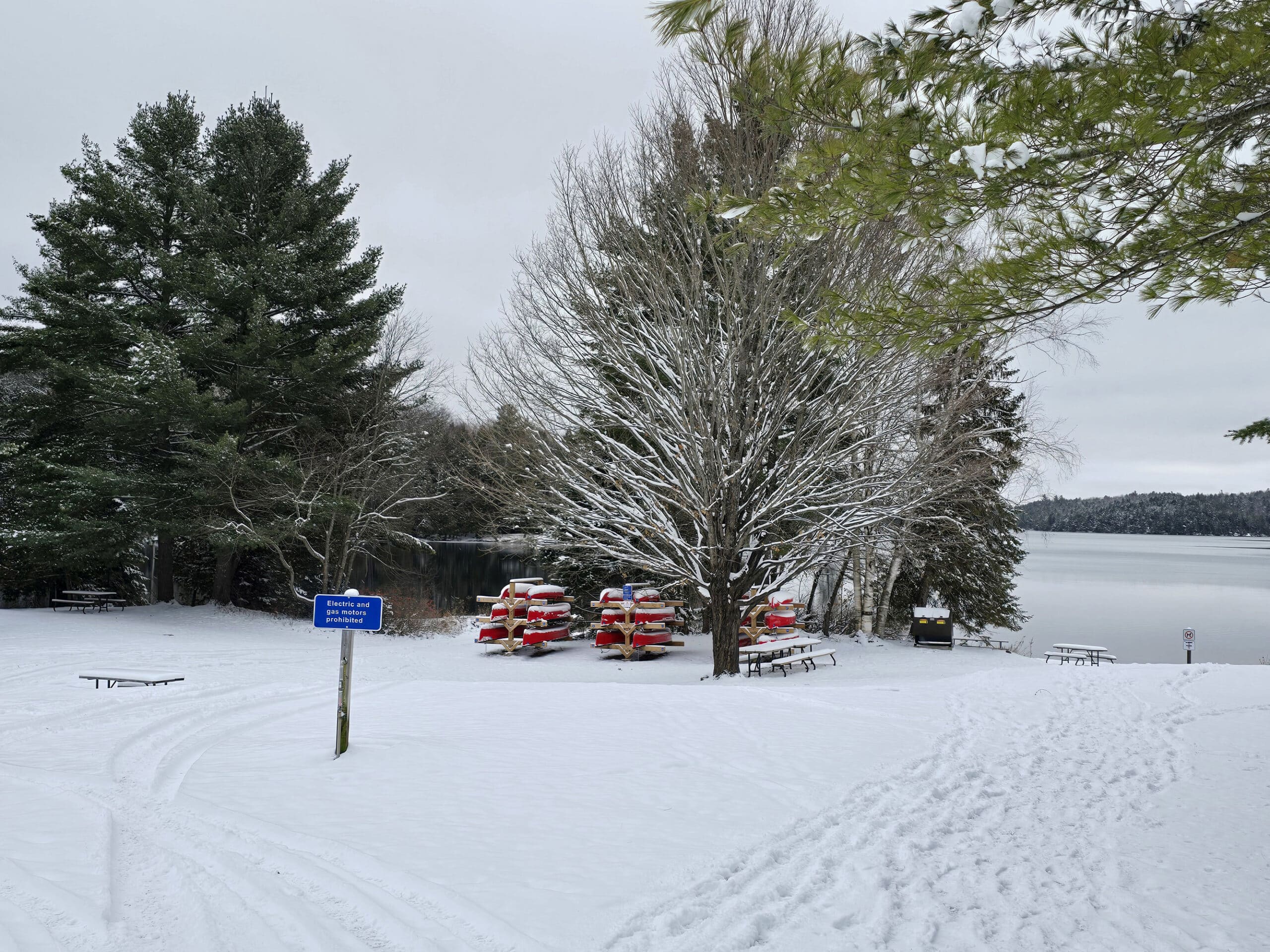 A snow covered back and canoe rental rack, with silent lake in the background.