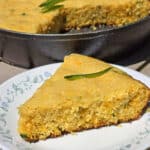 A pan of skillet jalapeno cheddar cornbread, with a slice on a plate.