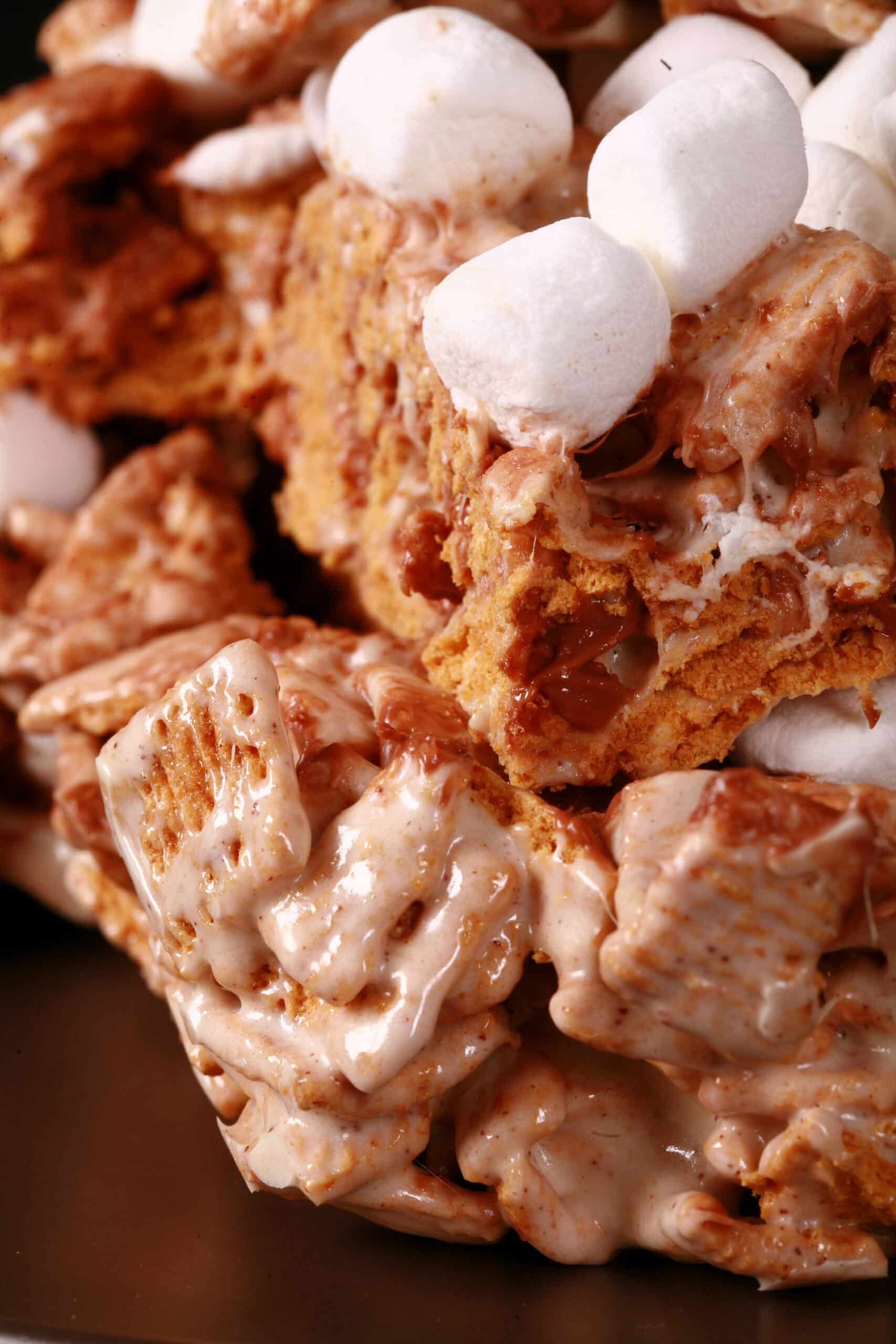 A plate of no-bake smores squares made with golden grahams cereal, melted marshmallows, mini marshmallows, browned butter, and chocolate chips.