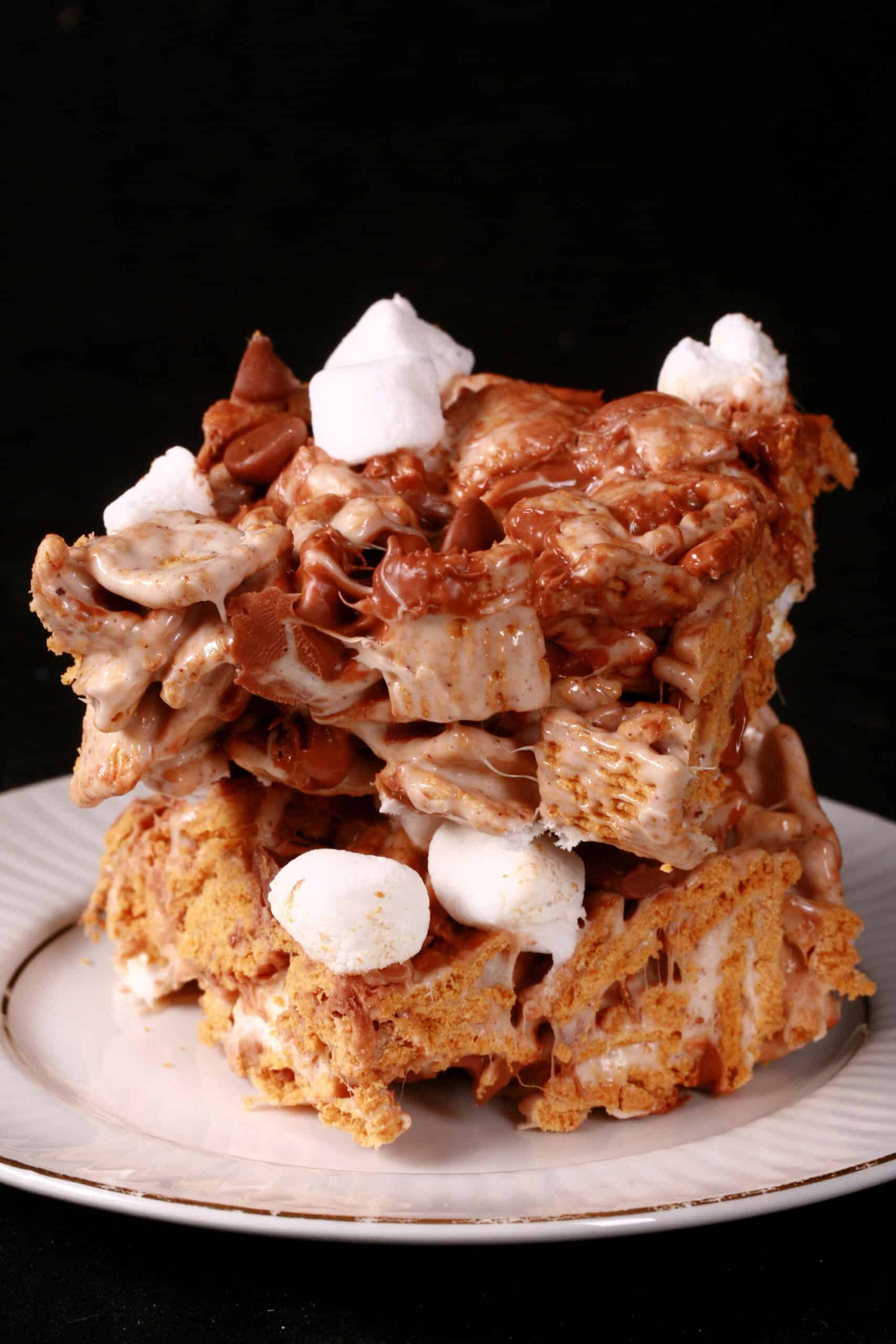 2 no-bake smores bars made with golden grahams cereal, melted marshmallows, mini marshmallows, browned butter, and chocolate chips.