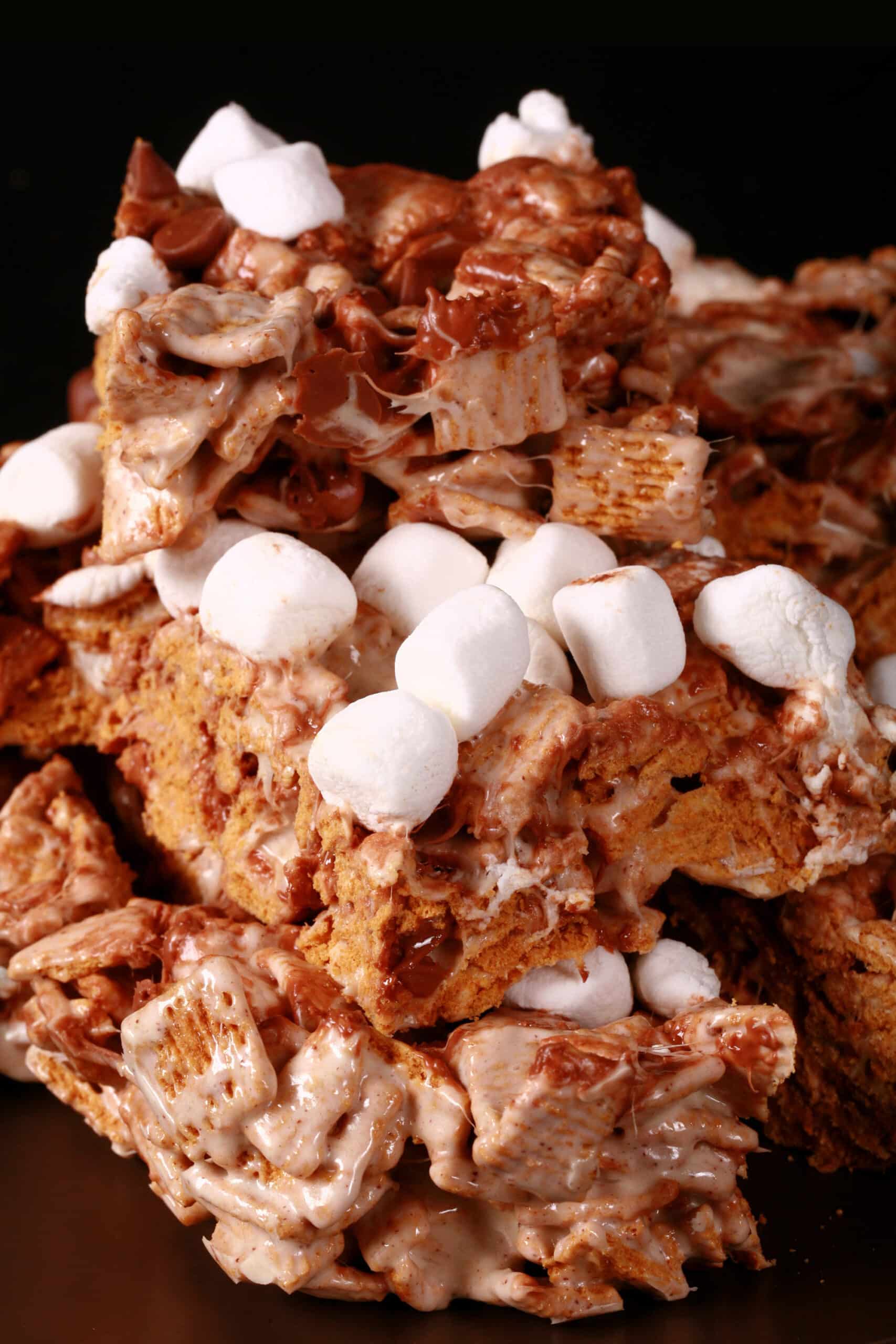 A plate of no-bake smores squares made with golden grahams cereal, melted marshmallows, mini marshmallows, browned butter, and chocolate chips.