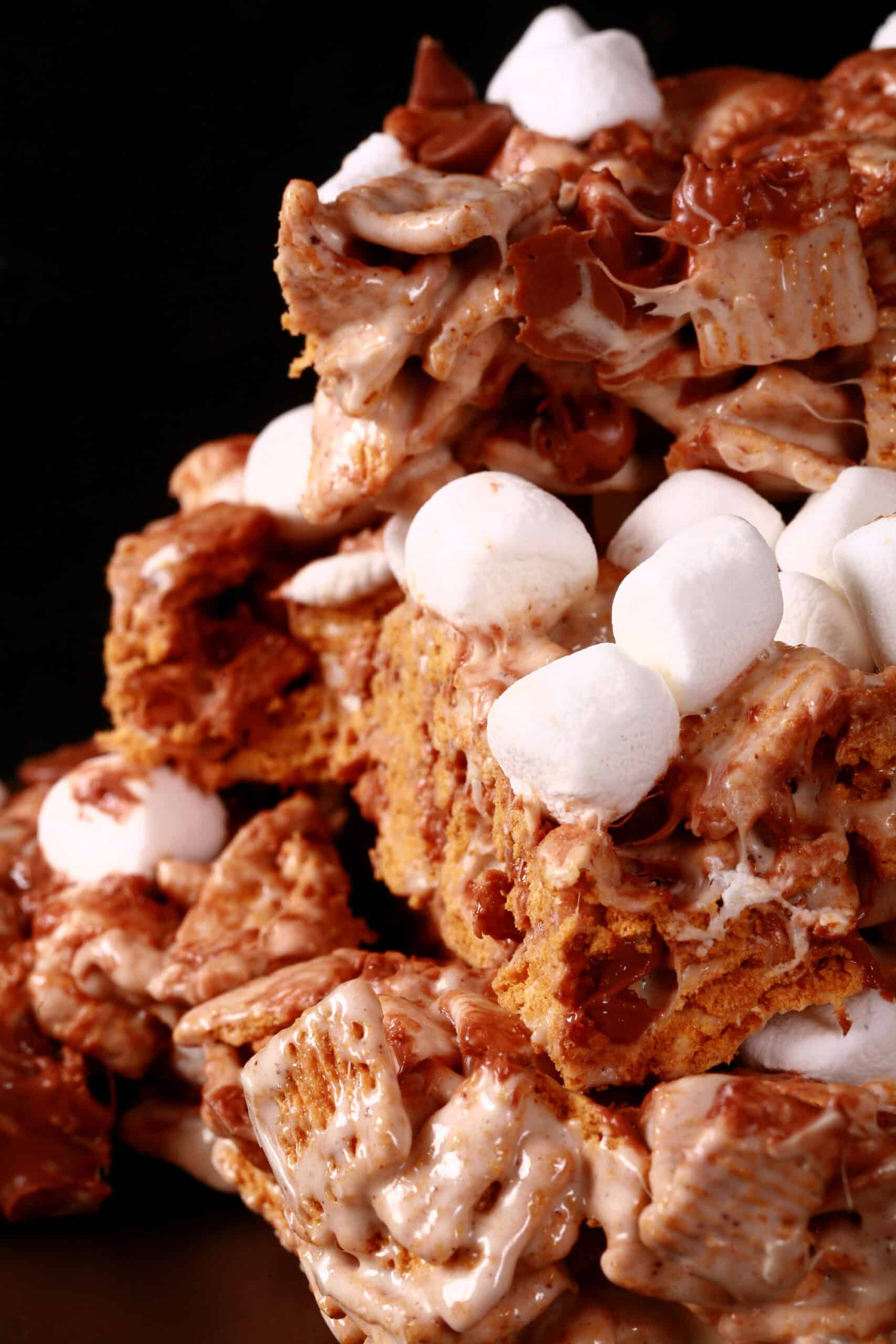 A plate of no-bake smores bars made with golden grahams cereal, melted marshmallows, mini marshmallows, browned butter, and chocolate chips.