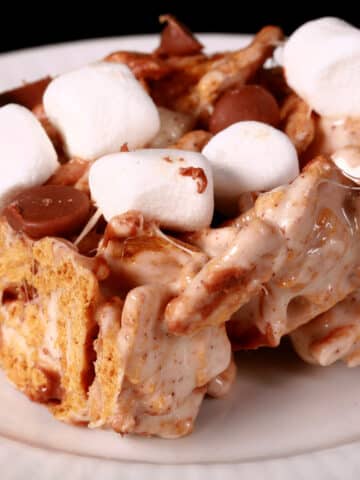 A no-bake smores bar made with golden grahams cereal, melted marshmallows, mini marshmallows, browned butter, and chocolate chips.