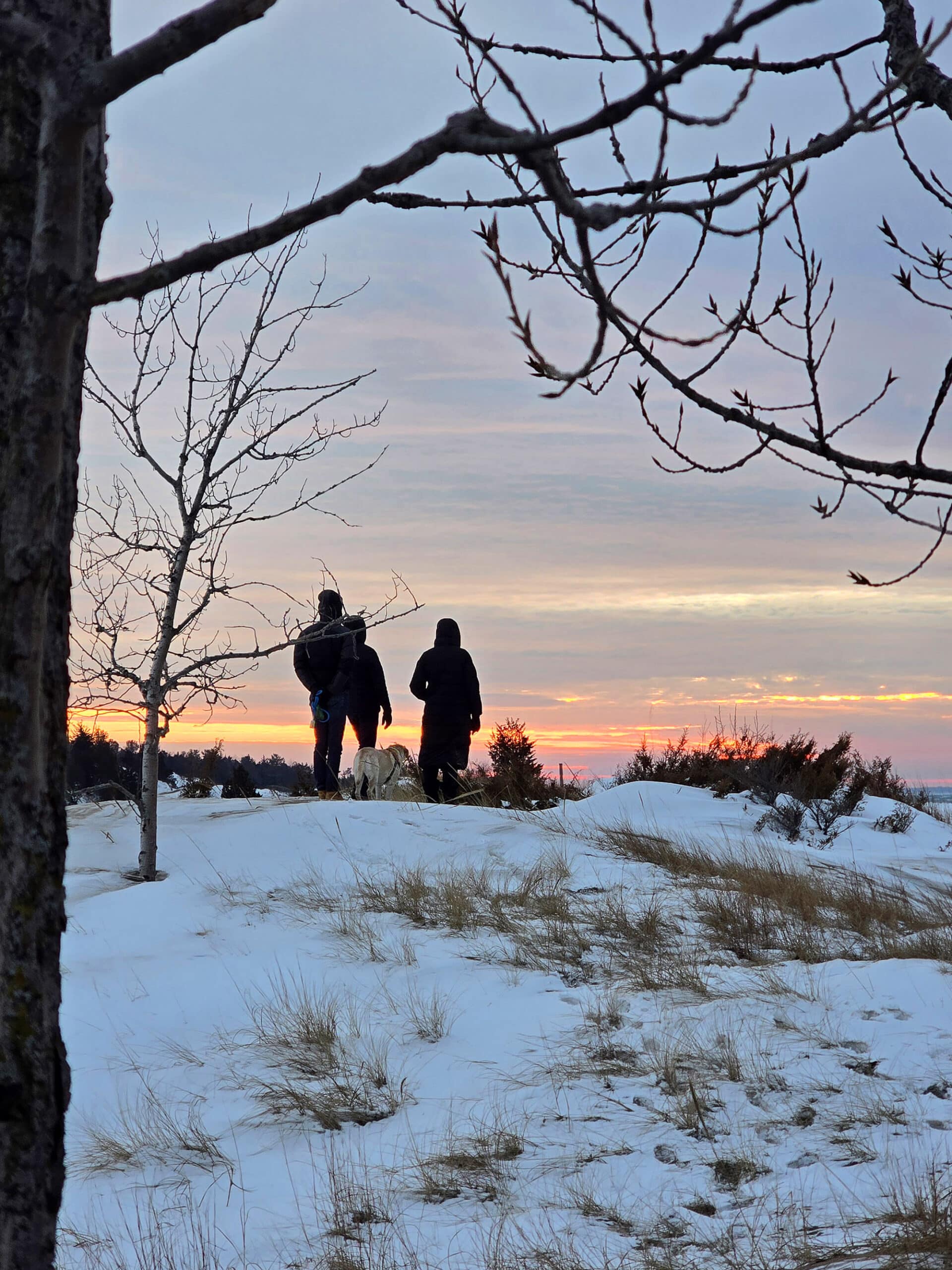 A family standing on a cliff, looking at a sunset over Lake Huron.