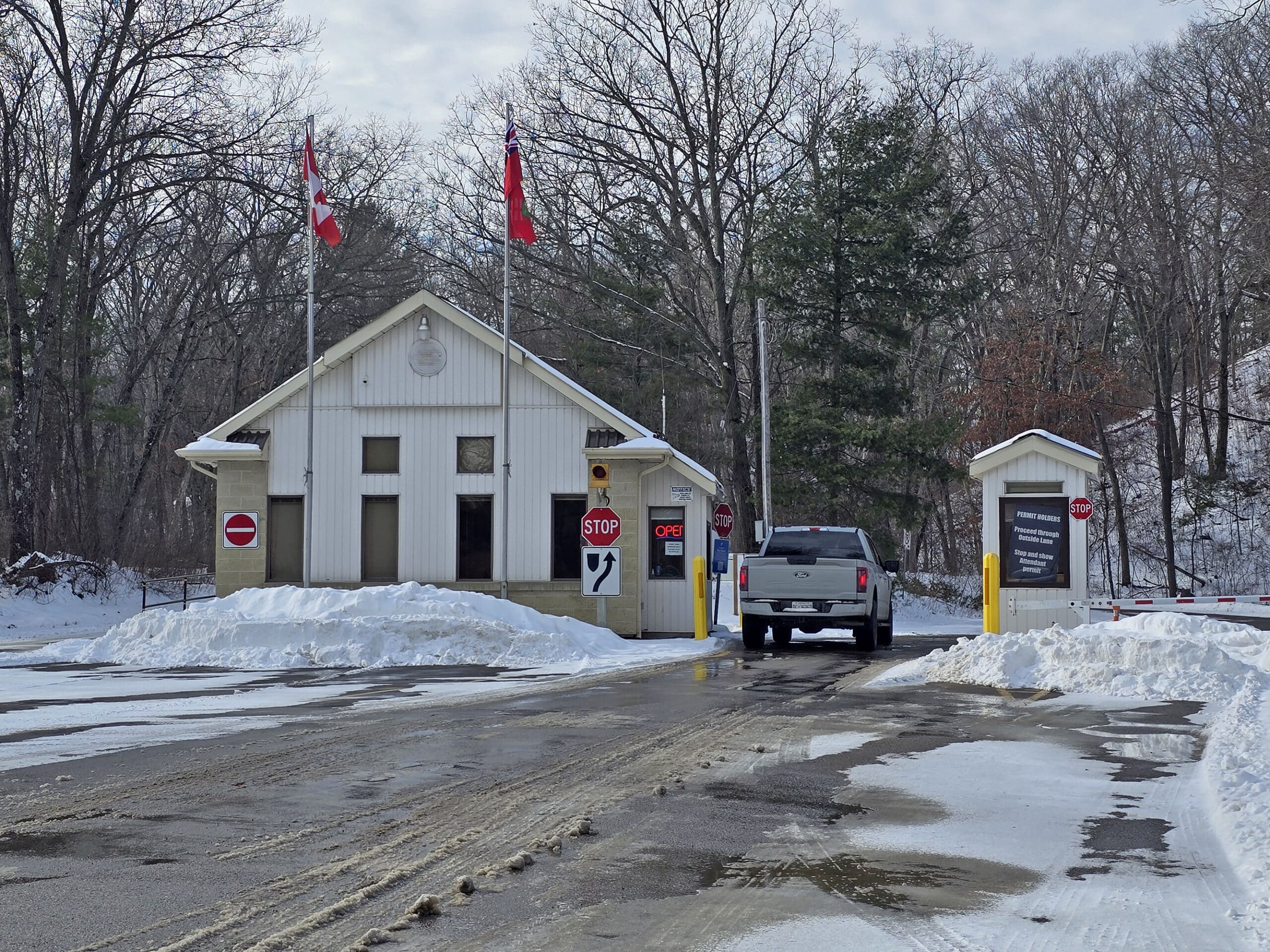 The front gate at pinery provincial park.  A white pickup truck is at the kiosk.