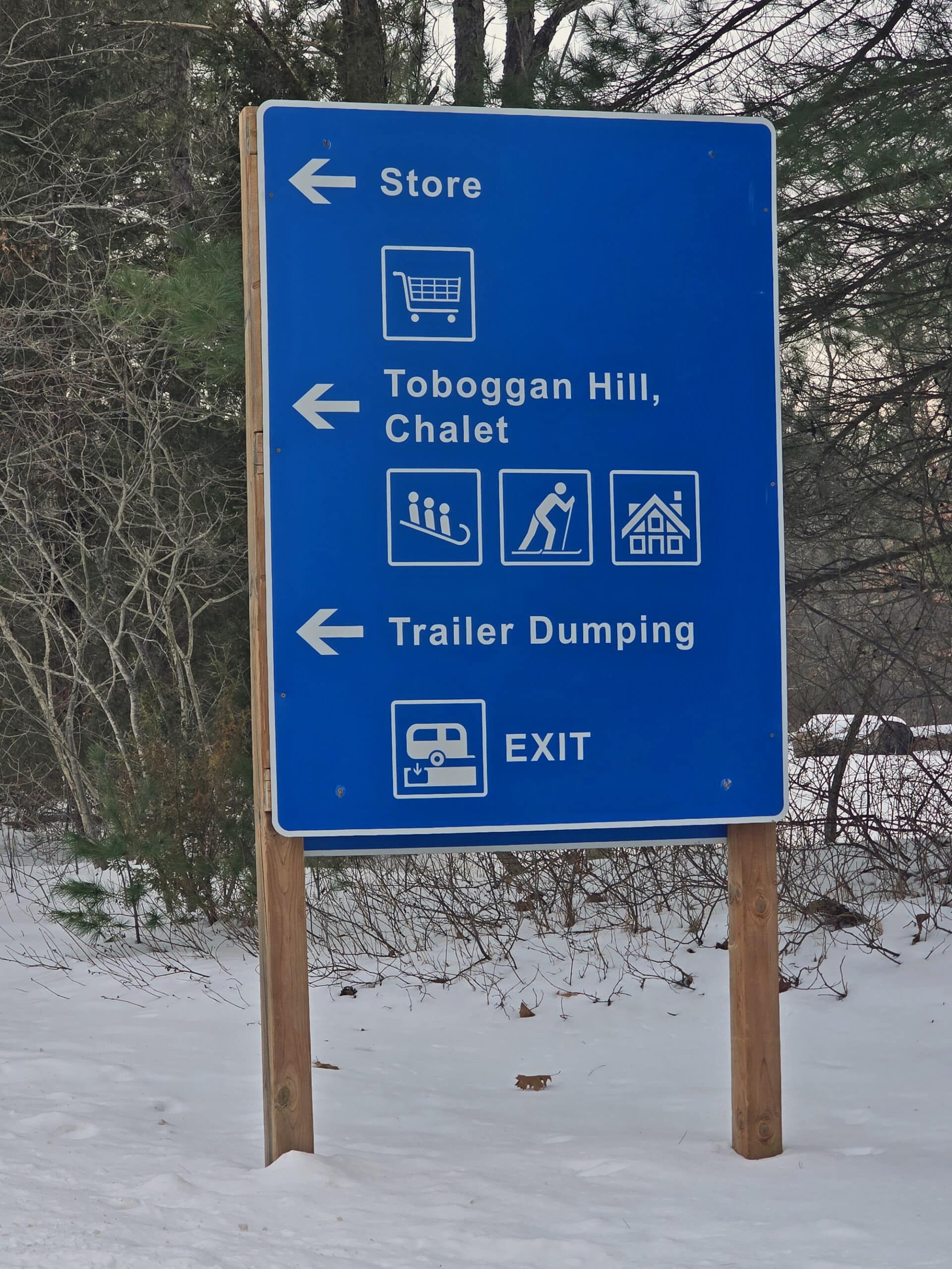 A blue and white campground sign showing where several attractions are.