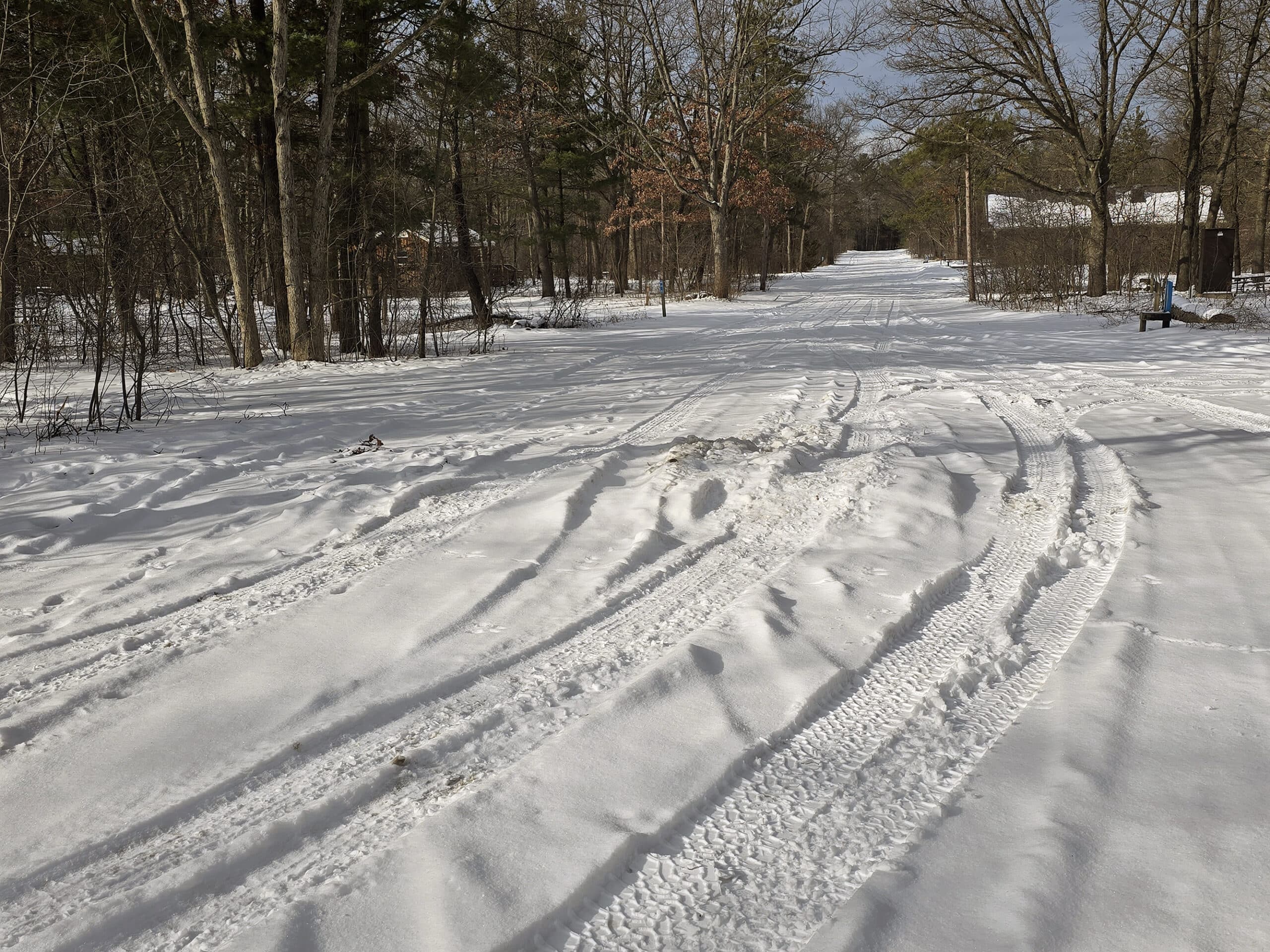 A poorly maintained campground road with big piles of snow built up.