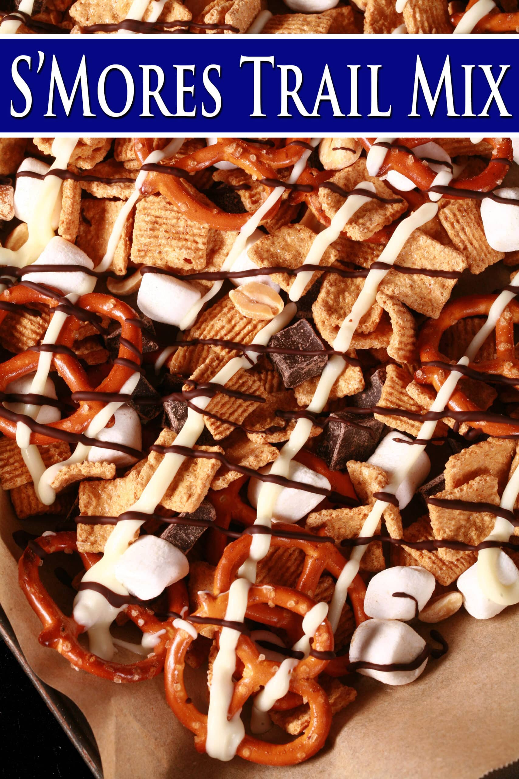 A pan of smores snack mix, with golden grahams cereal, chocolate chunks, peanuts, pretzels, and mini marshmallows, drizzled with white and milk chocolate. Overlaid text says Smores Trail Mix,