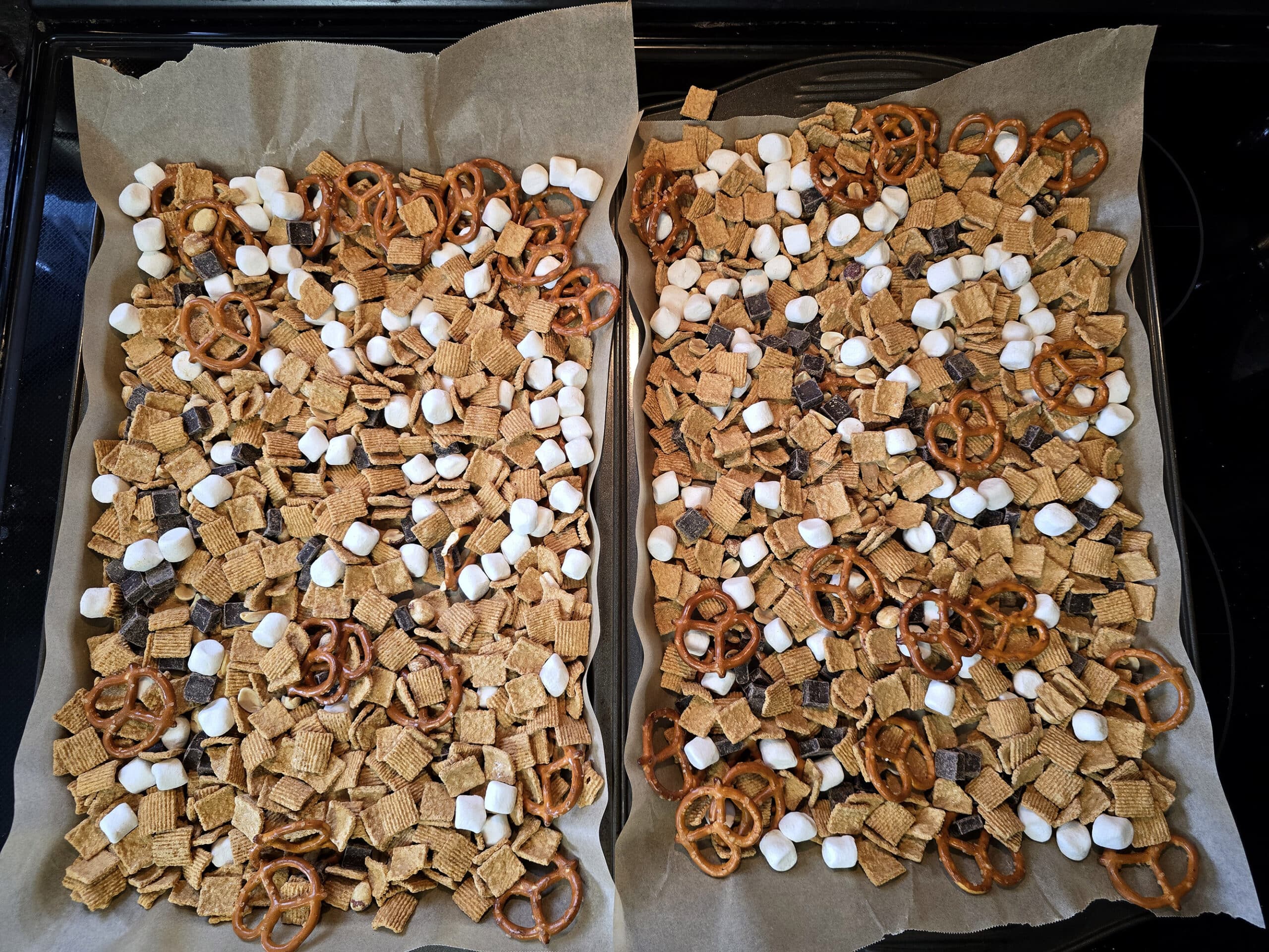 Smores trail mix spread out over 2 baking sheets.