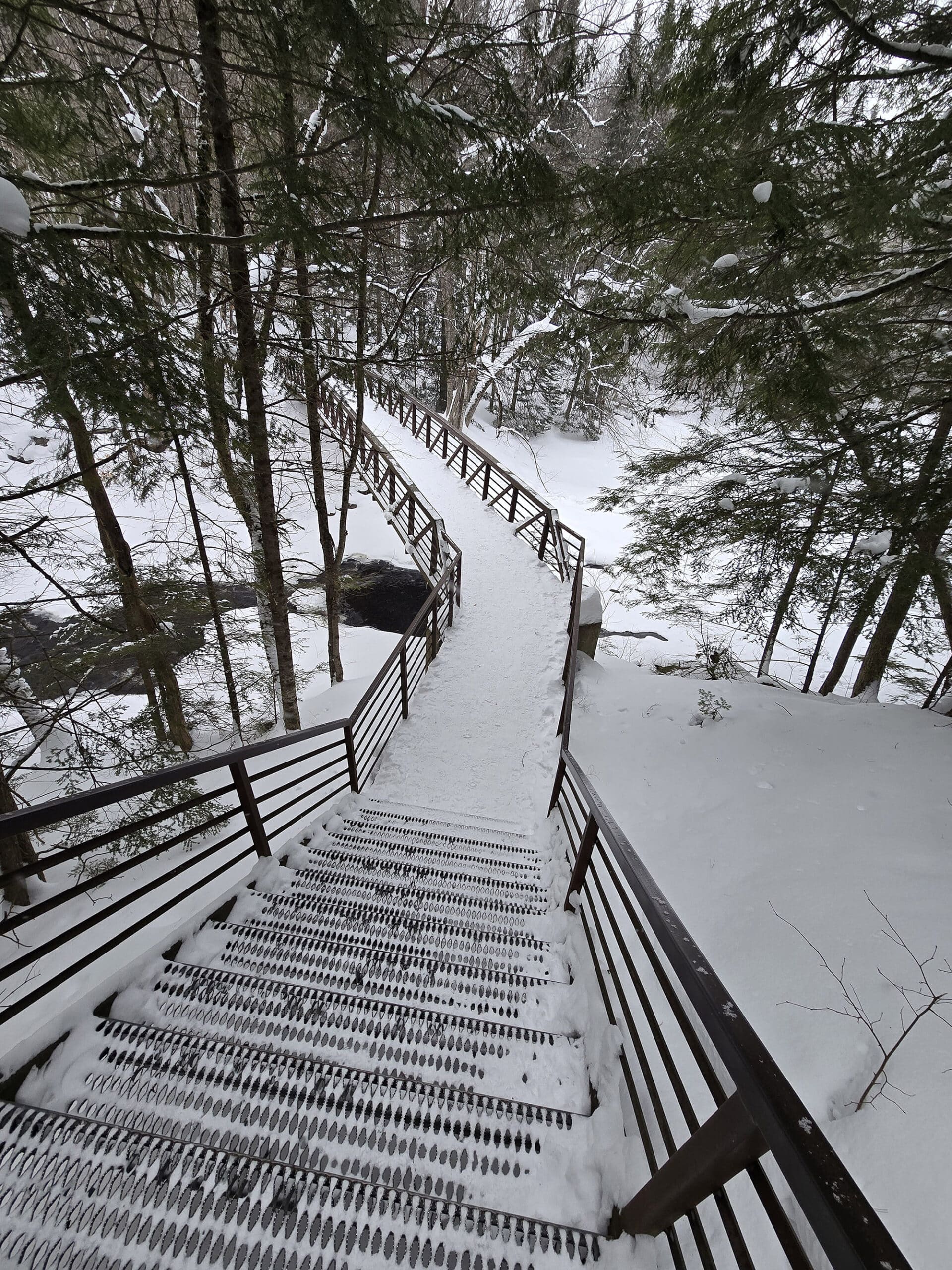 A set of outdoor metal stairs over stubb's falls in winter.