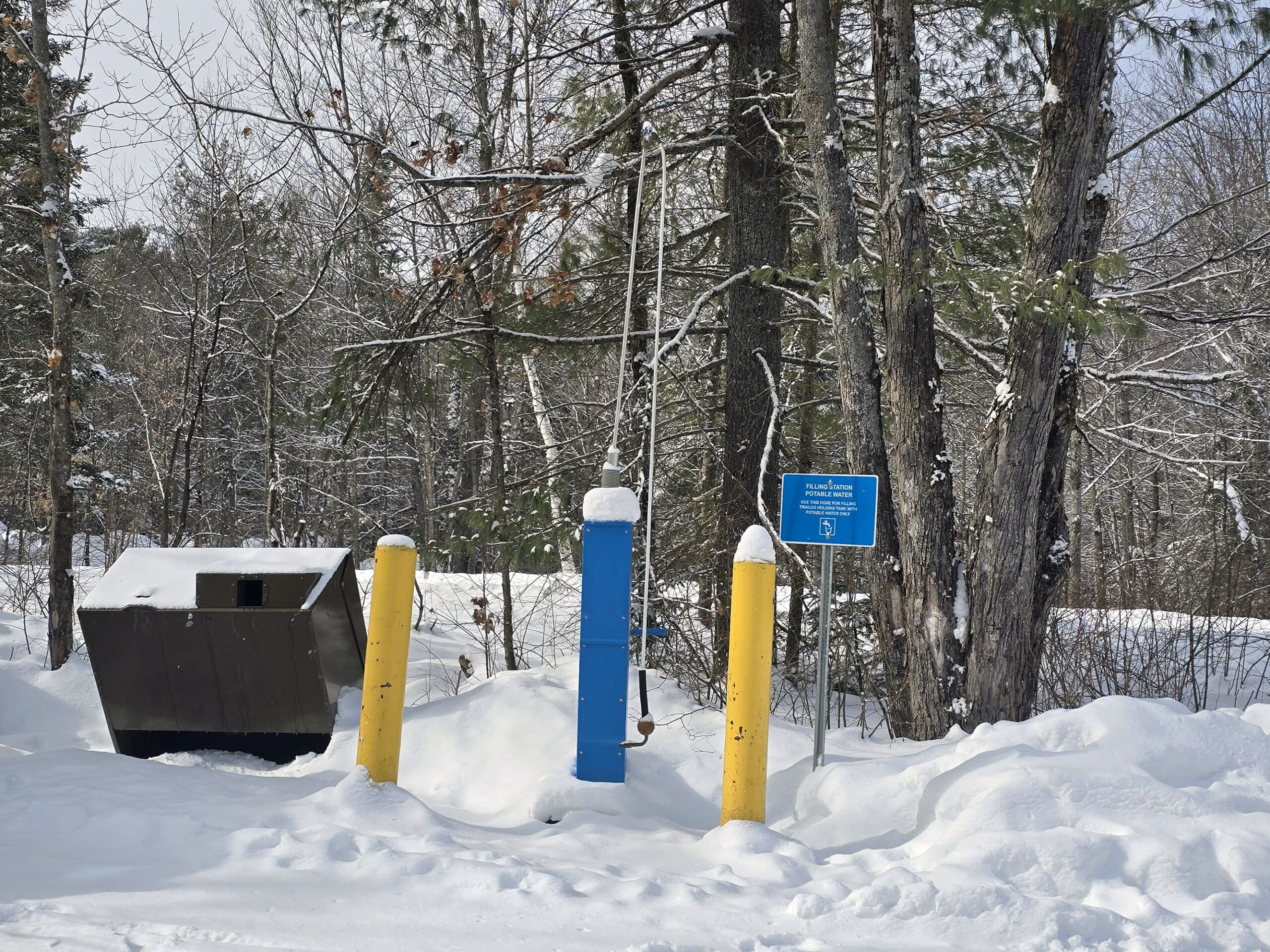 A trailer filling water post in winter.