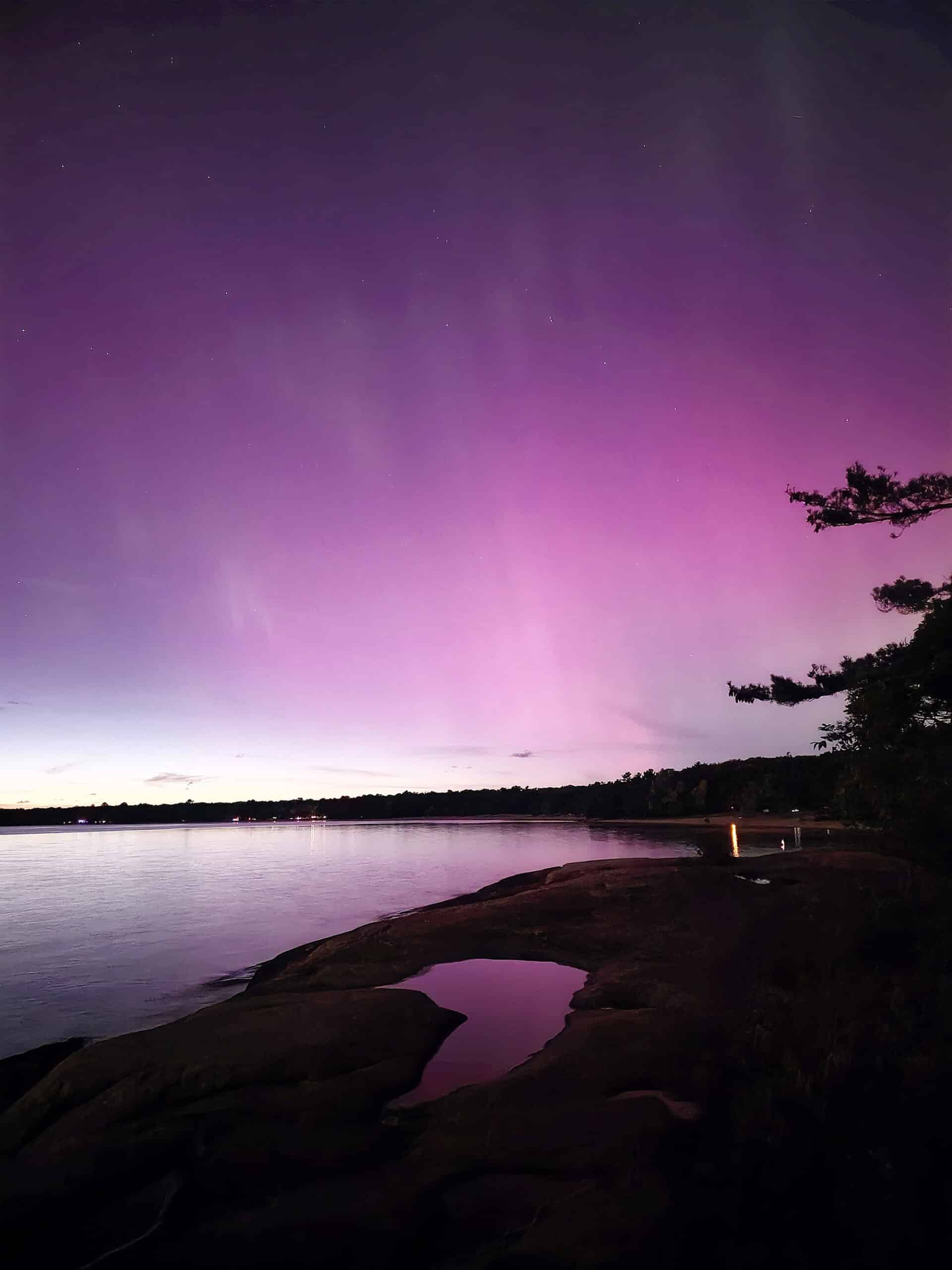 Pink and Purple aurora borealis as the sun sets off to the side.