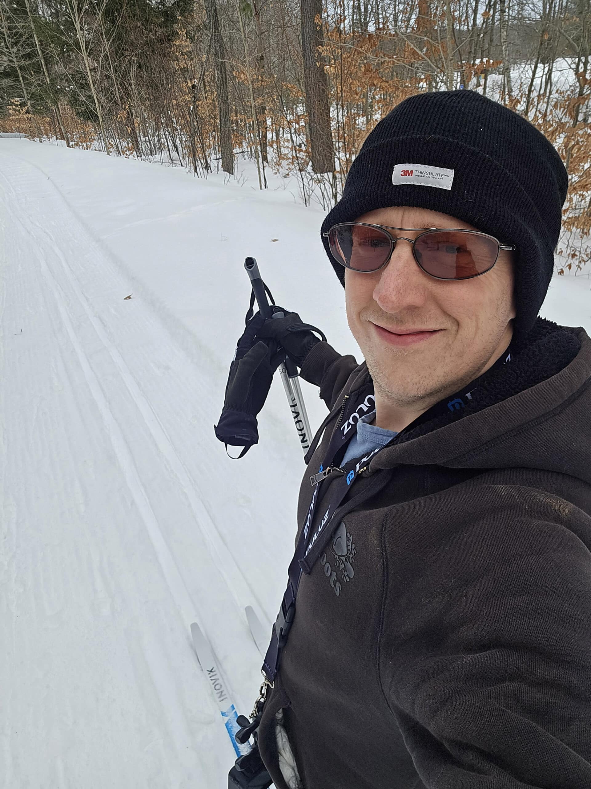 A middle aged white man taking a selfie on a ski trail.