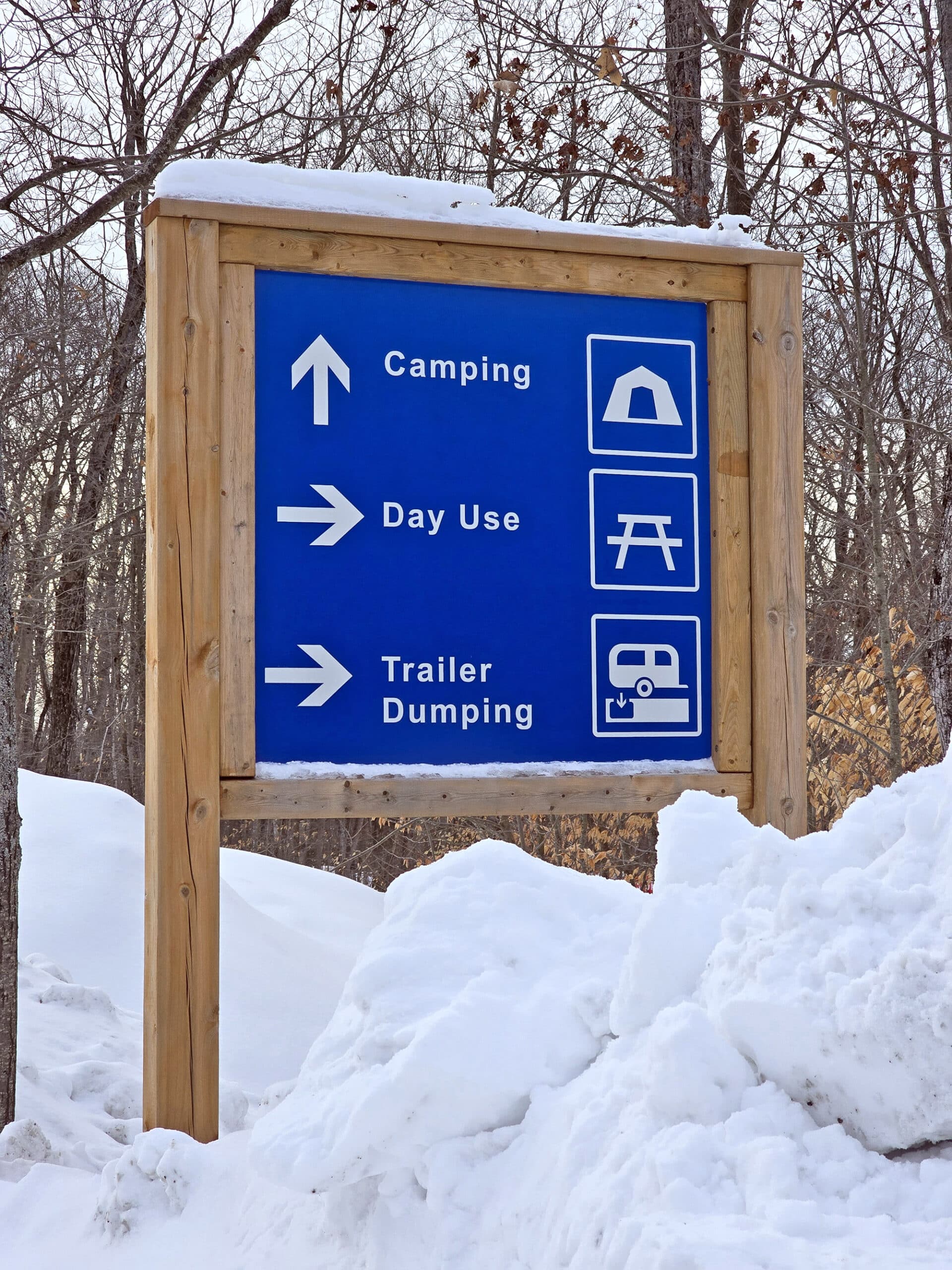 A blue and white road sign showing how to get to the camping, day use, and trailer dump areas at killbear.