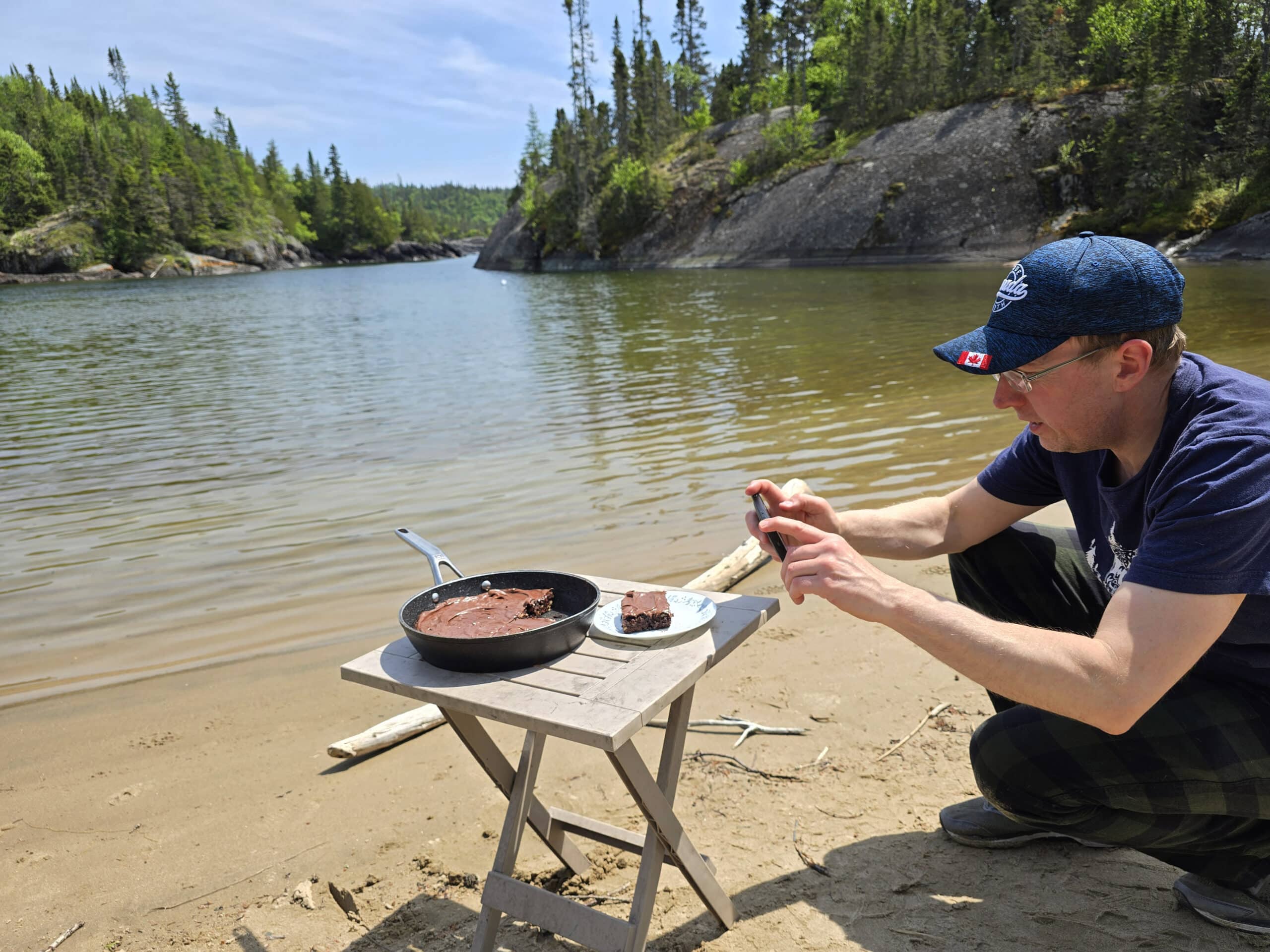 A man photographing campfire brownies on the shore of lake superior at Pukaskwa national park.