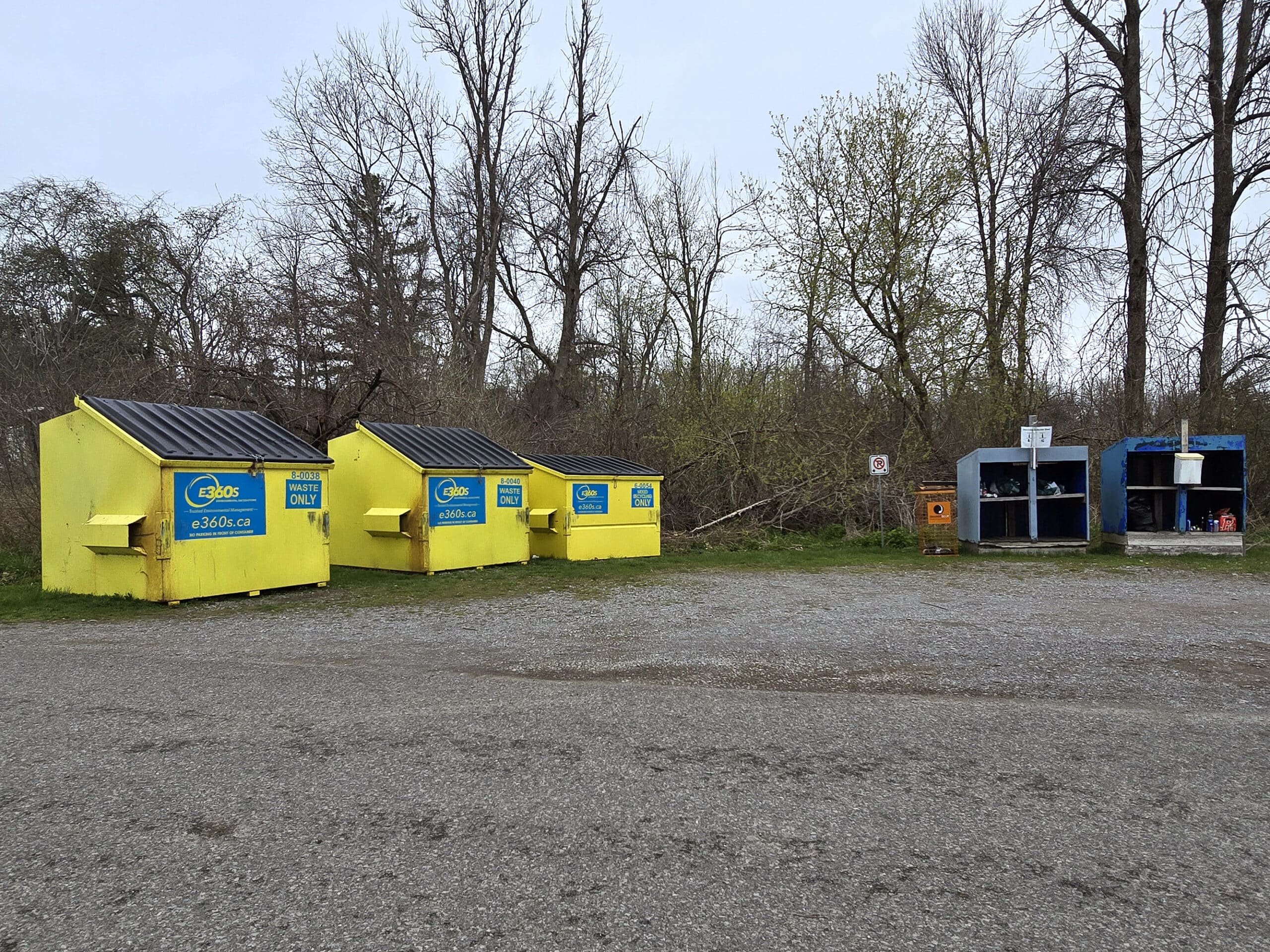 Several large yellow garbage bins and a bottle recycling shelf at Presqu’ile Provincial Park.