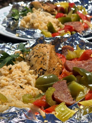 2 Cajun chicken foil packet meals, with marinated chicken breast, seasoned rice, red peppers, green peppers, celery, onion, and sausage.
