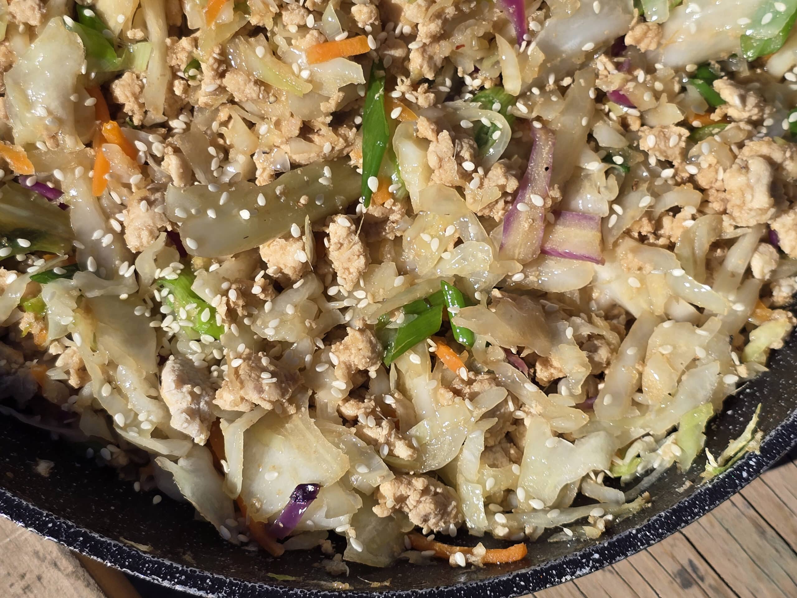 A pan of egg roll in a bowl - shredded cabbage, ground beef, and more.