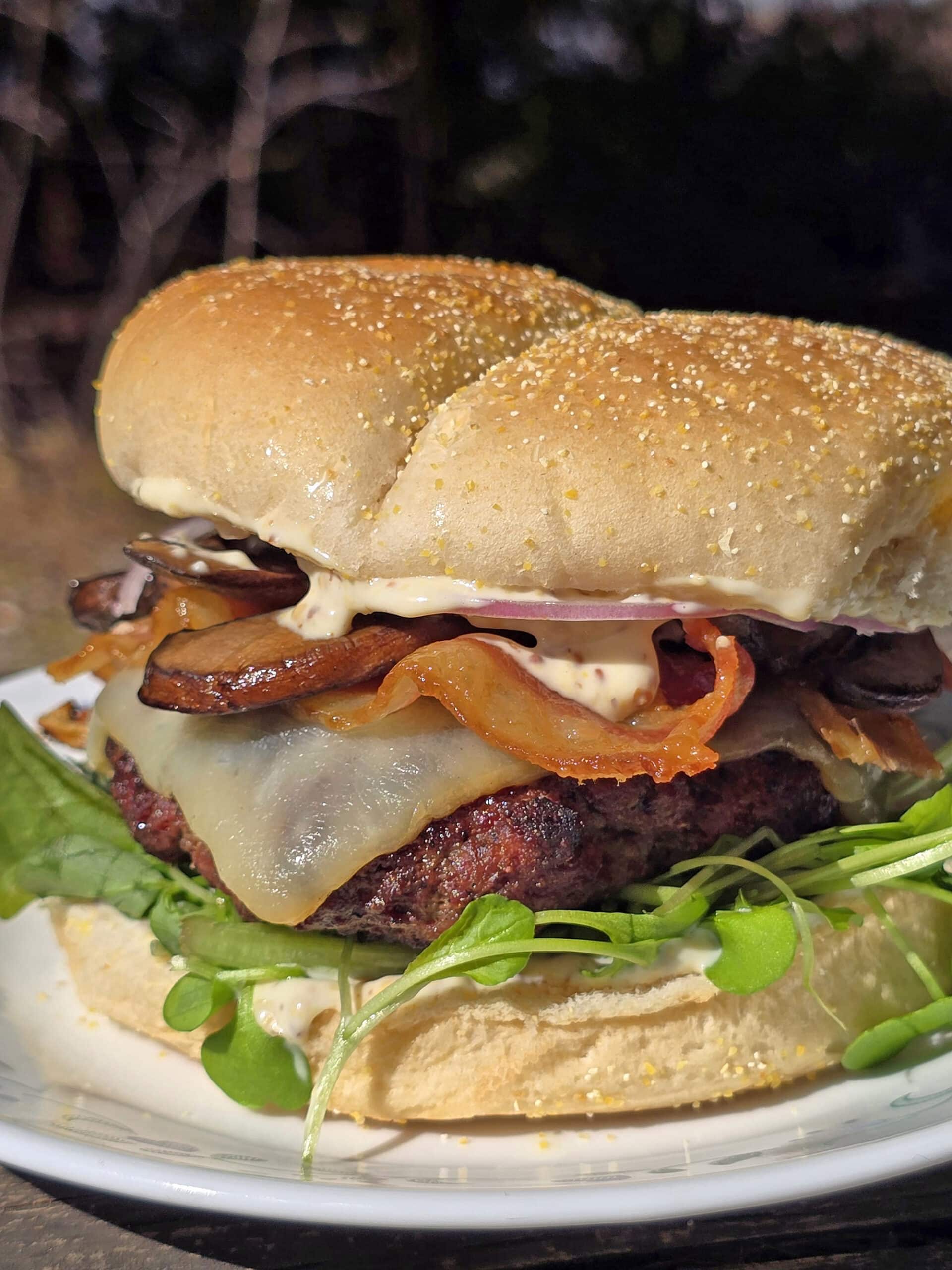 A loaded elk burger with bacon, smoked cheddar, sauteed mushrooms, and dijonnaise.