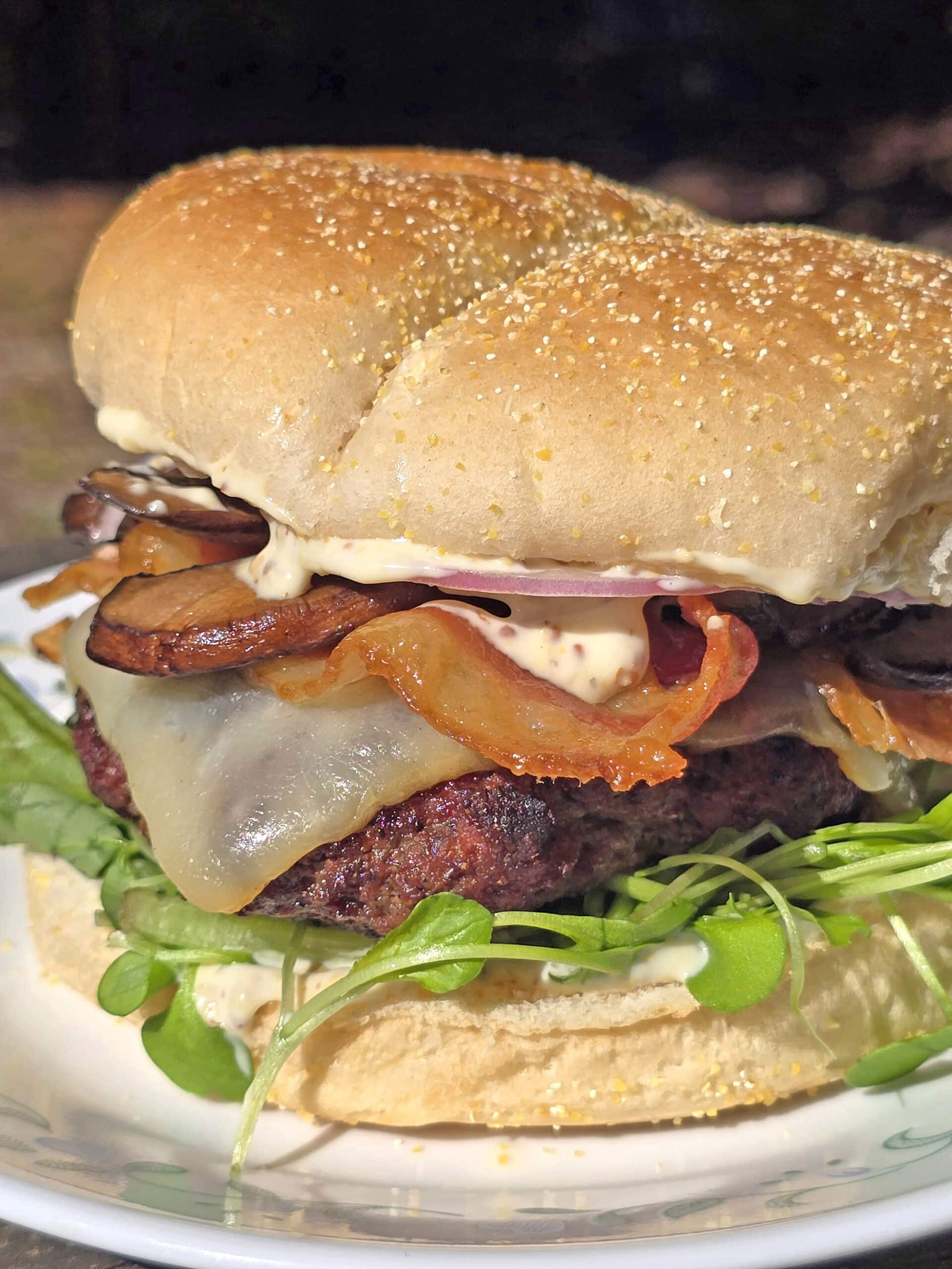A loaded elk burger with bacon, smoked cheddar, sauteed mushrooms, and dijonnaise.