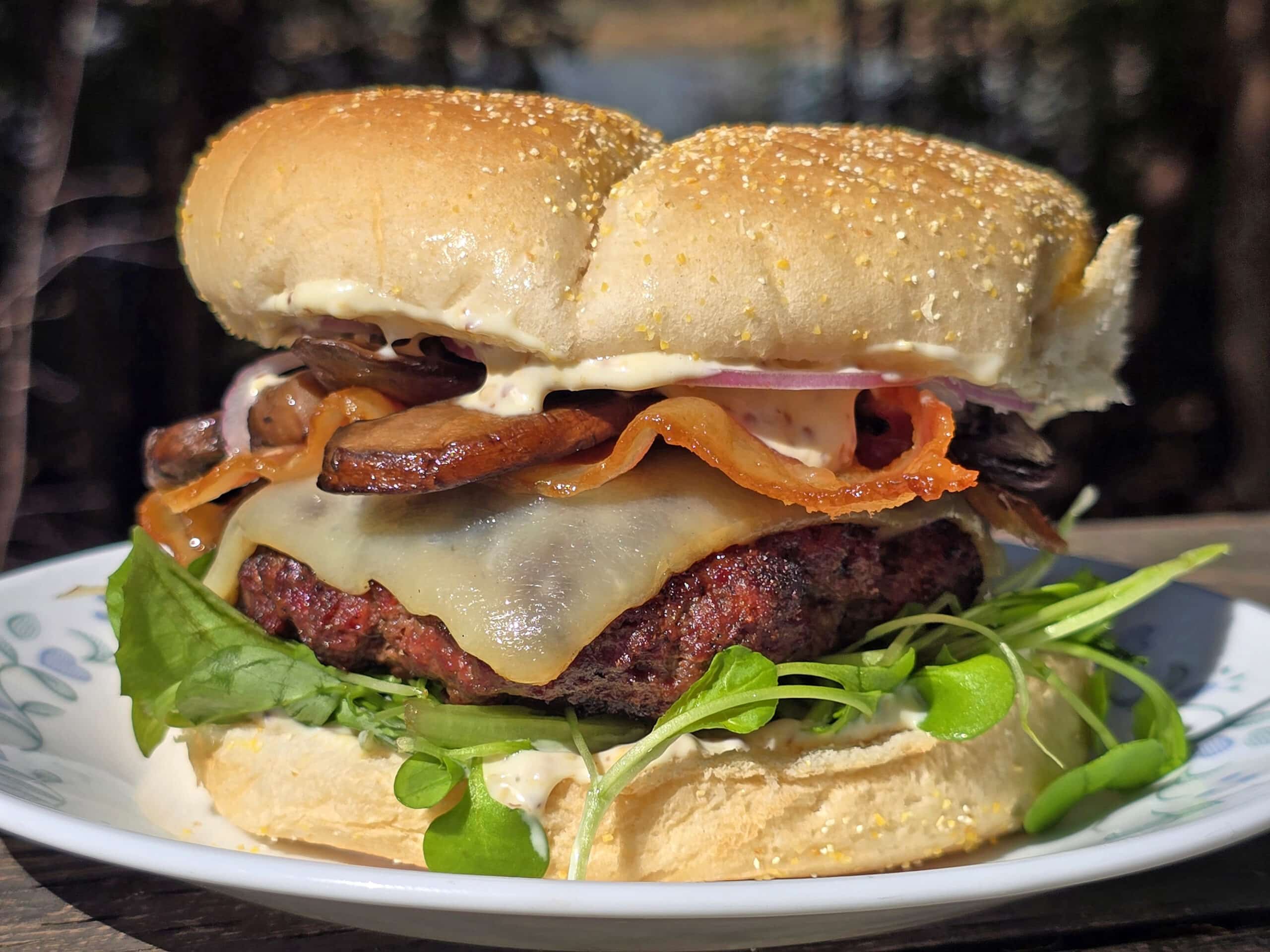 A loaded elk burger with bacon, smoked cheddar, sauteed mushrooms, and dijonnaise.