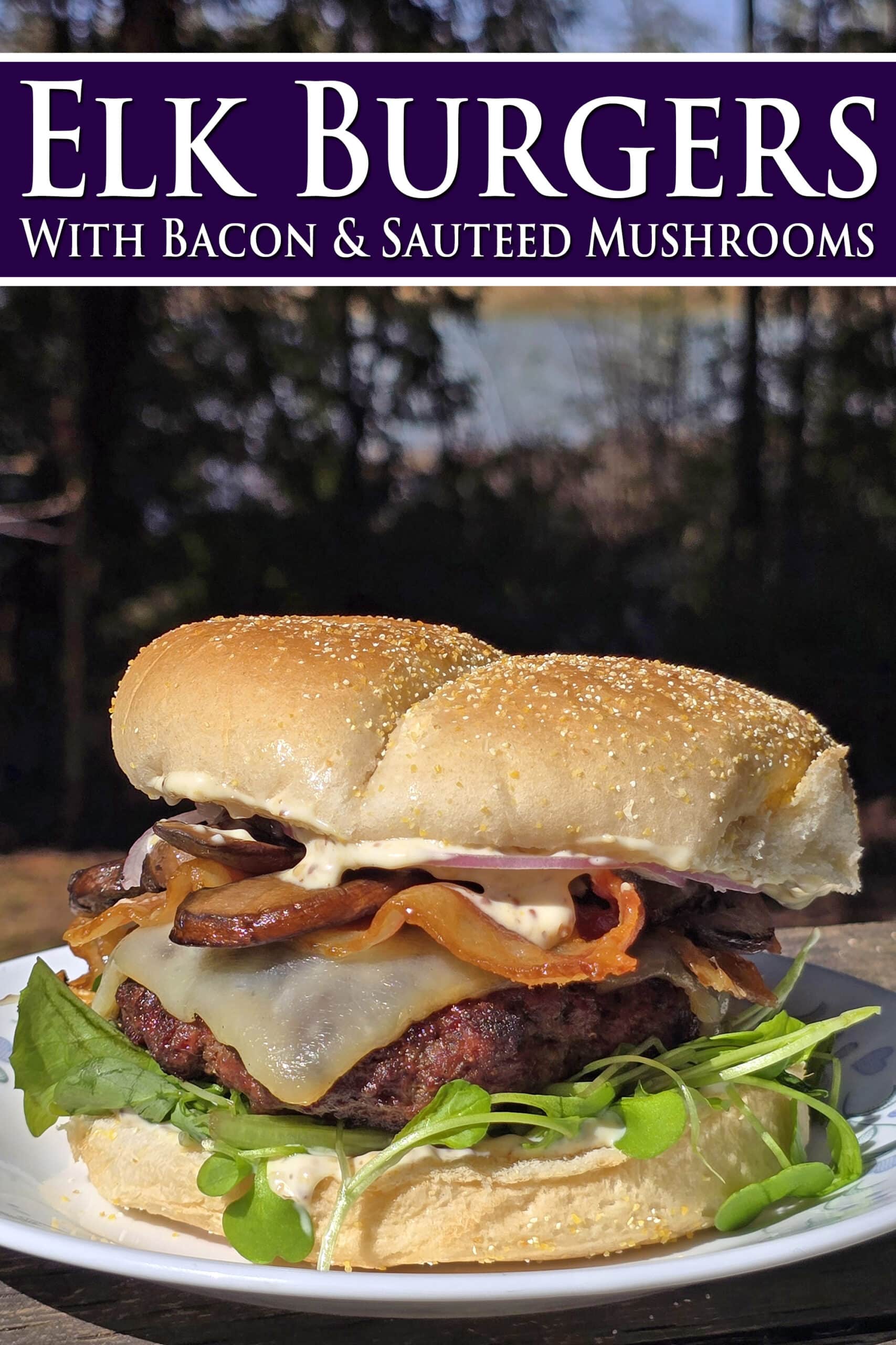 A loaded elk burger with bacon, smoked cheddar, sauteed mushrooms, and dijonnaise. Overlaid text says elk burgers with bacon and sauteed mushrooms.
