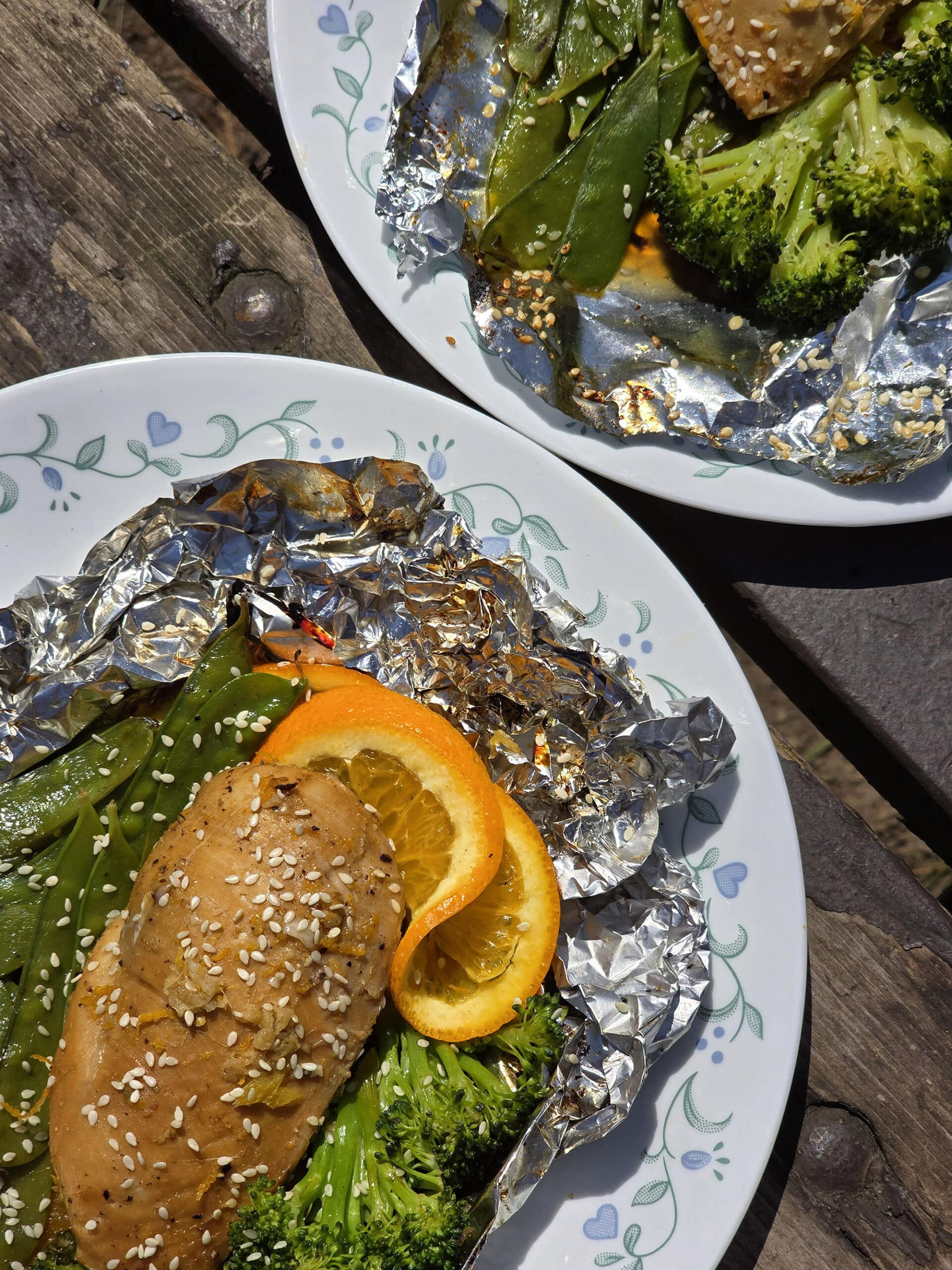 2 portions of ginger orange chicken foil packet meals, with broccoli and peas.