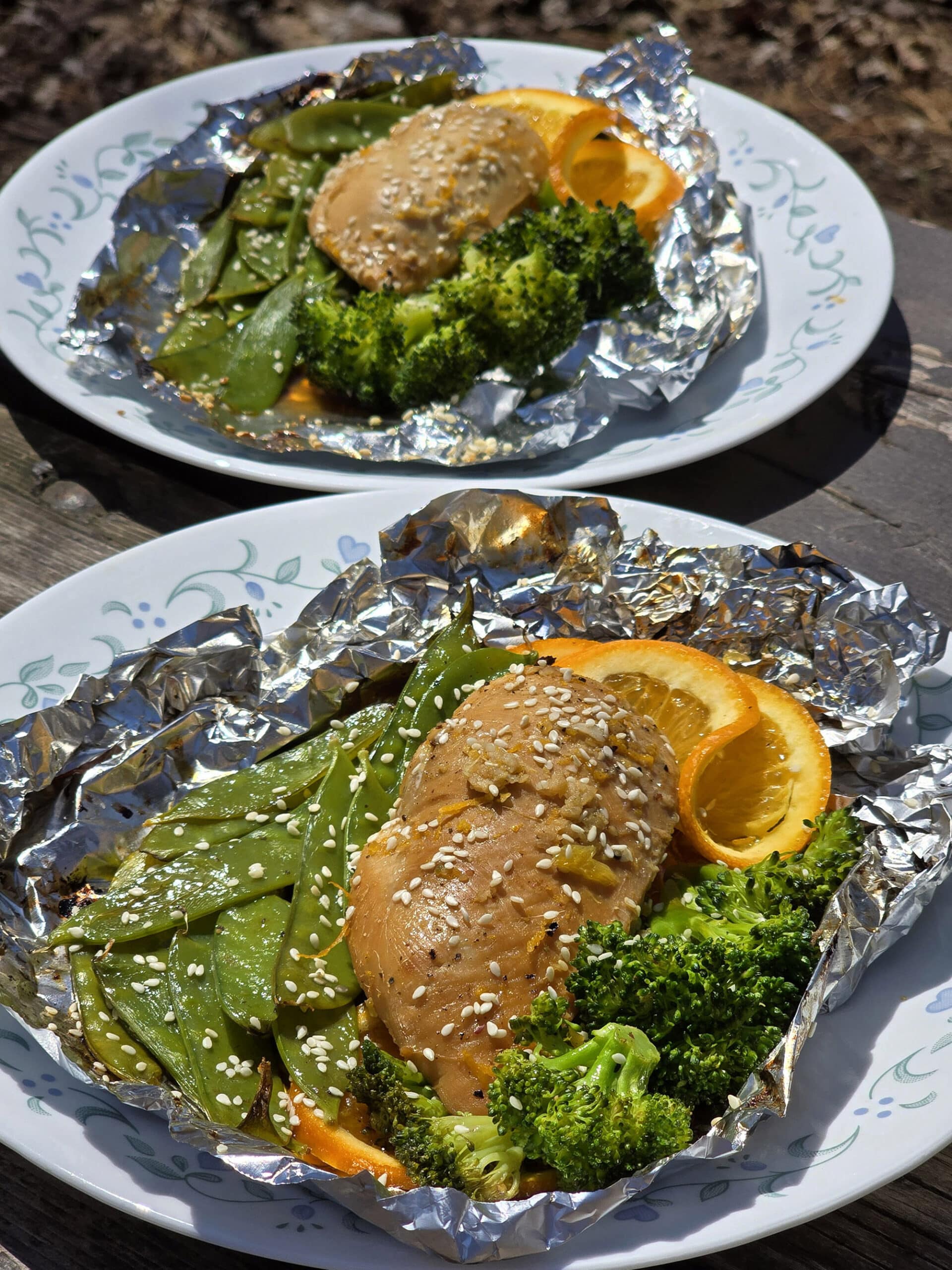 2 portions of ginger orange chicken foil packet meals, with broccoli and peas.