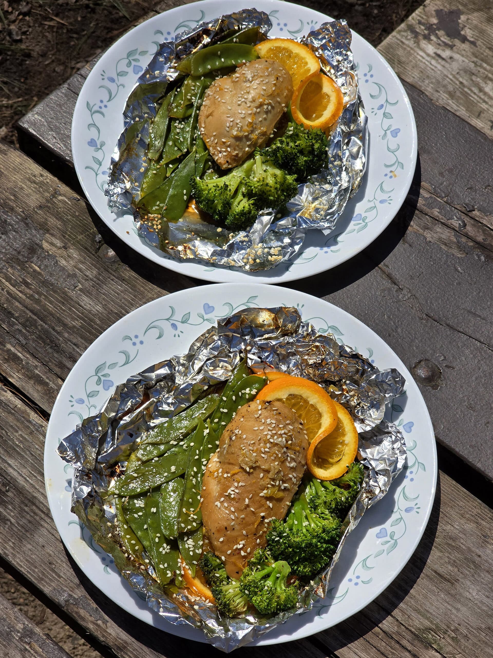 2 portions of ginger orange chicken foil packet meals, with broccoli and peas.